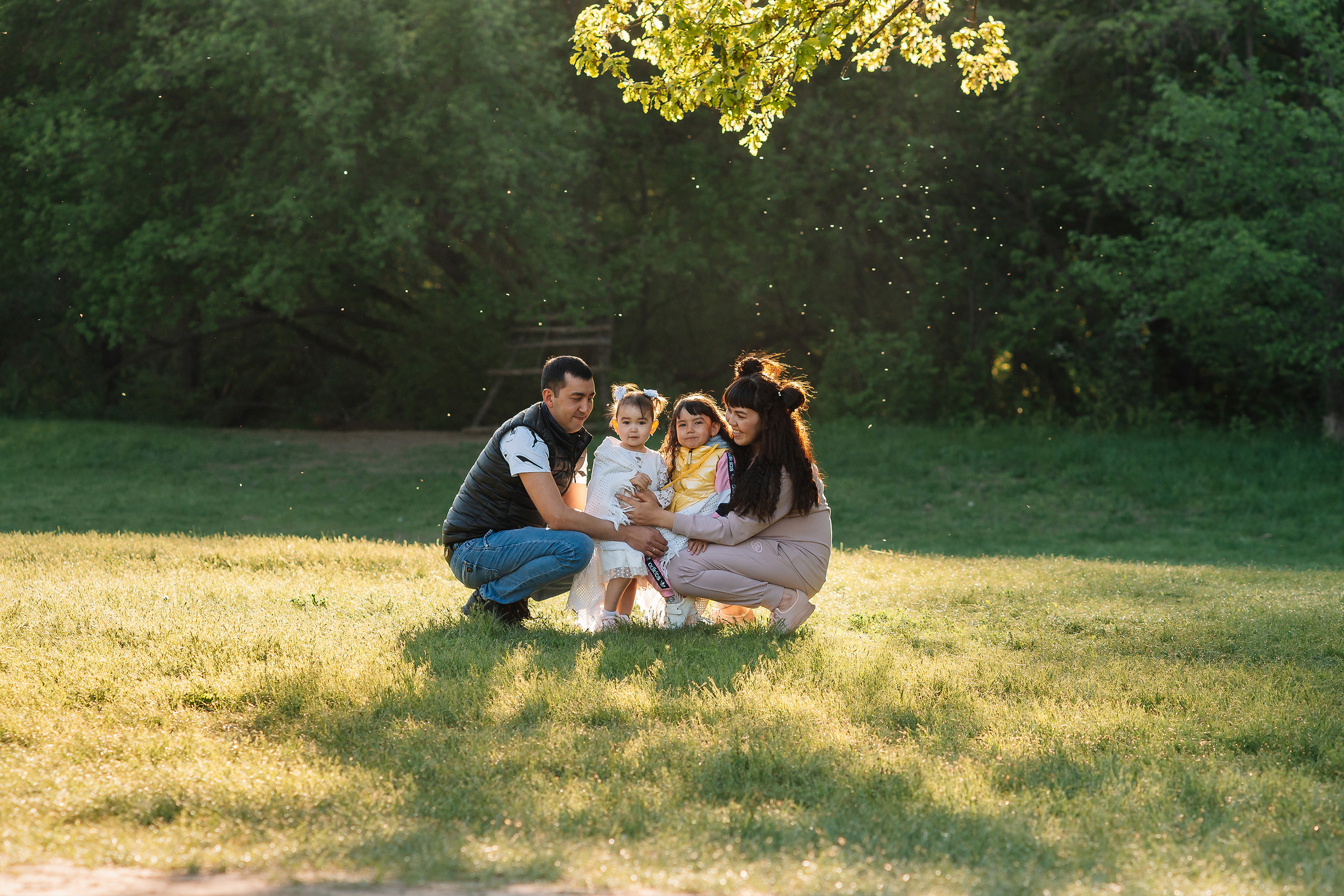 Цена фотосессии в Энгельсе не так важна, когда получаются такие волшебные кадры как этот. Прекрасная молодая семья с двумя своими дочками сидят на зеленой лужайке освещаемые сзади лучами закатного солнца, а в воздухе пылинки подсвеченные солнцем кажутся светлячками.