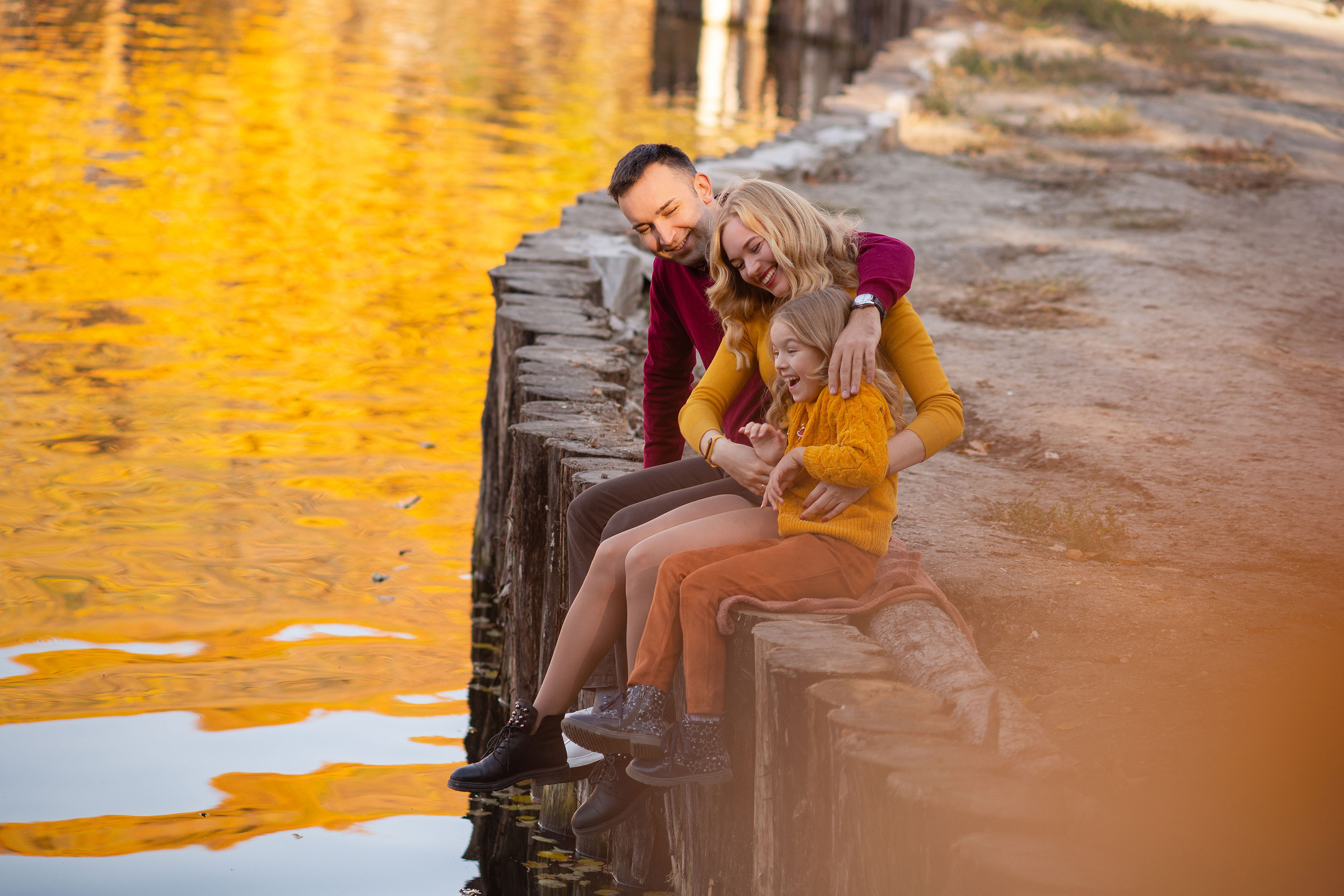 Молодая семья с дочкой сидят на берегу пруда Ударник в Саратове.