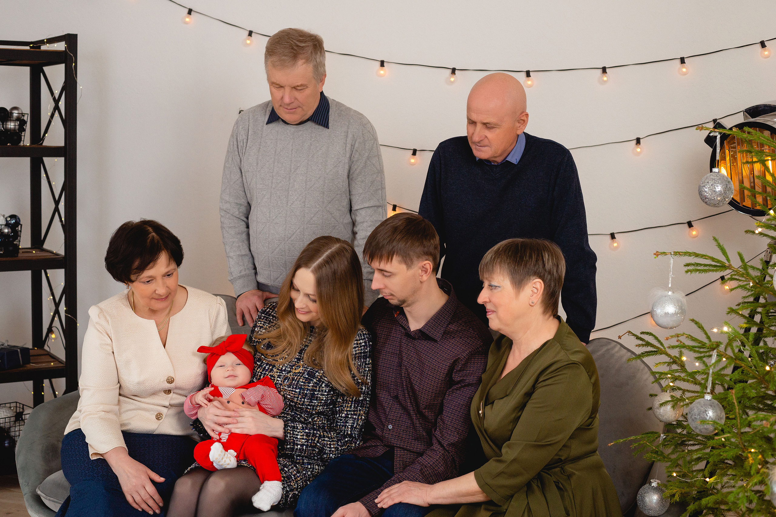 Отец с матерью и их родителями умиляются своей дочкой в новогоднем костюме.