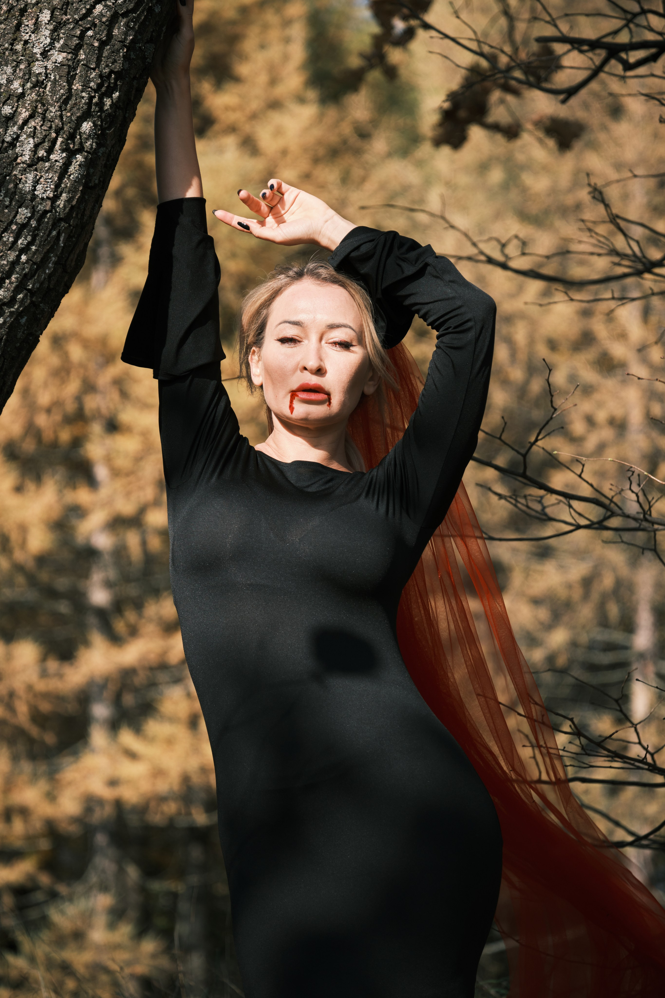 девушка Вампир с кровью на губах стоит на солнце