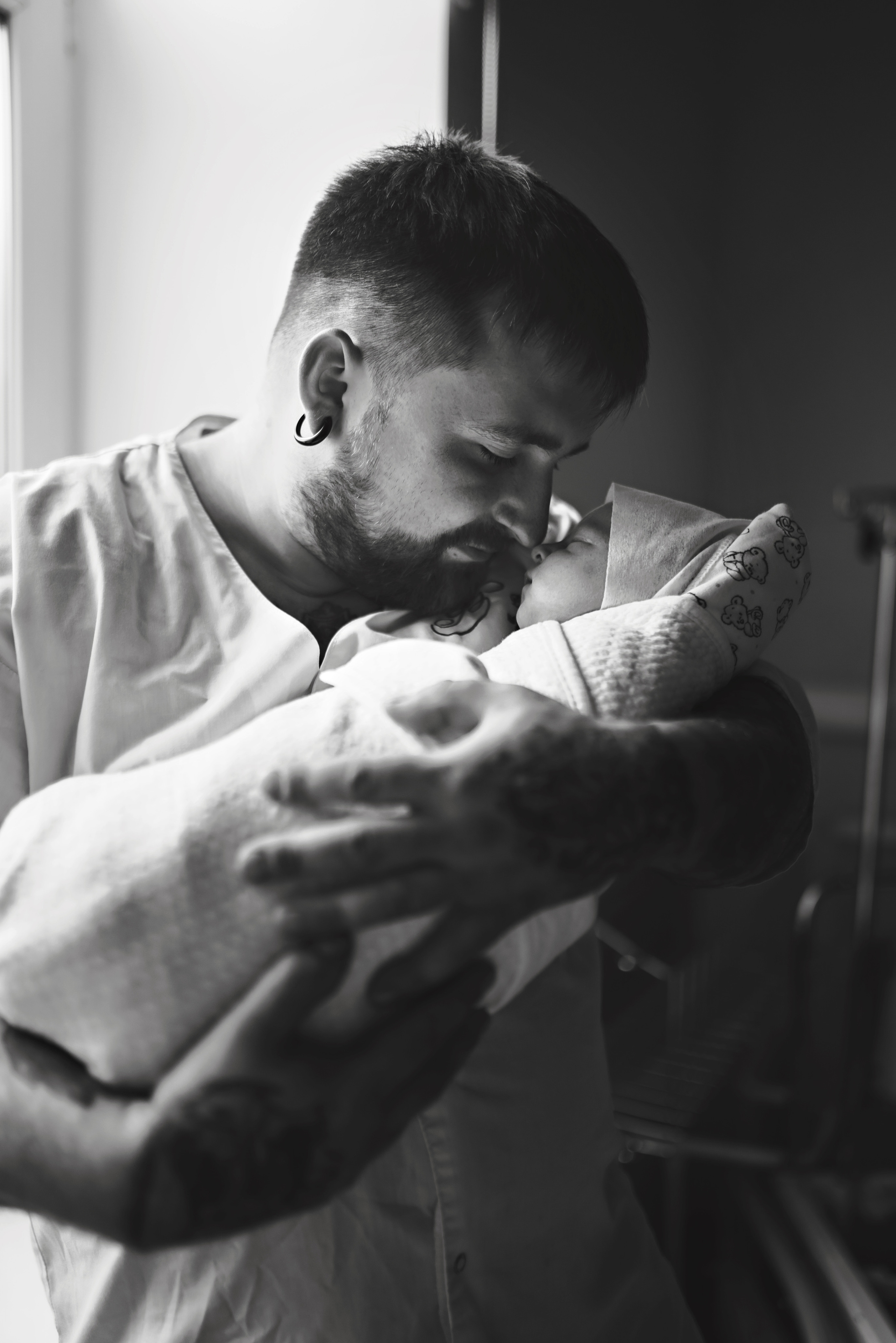 Father holding newborn baby close, tender moment, during birth photography session in Austin, Texas by Anny Smirnova.