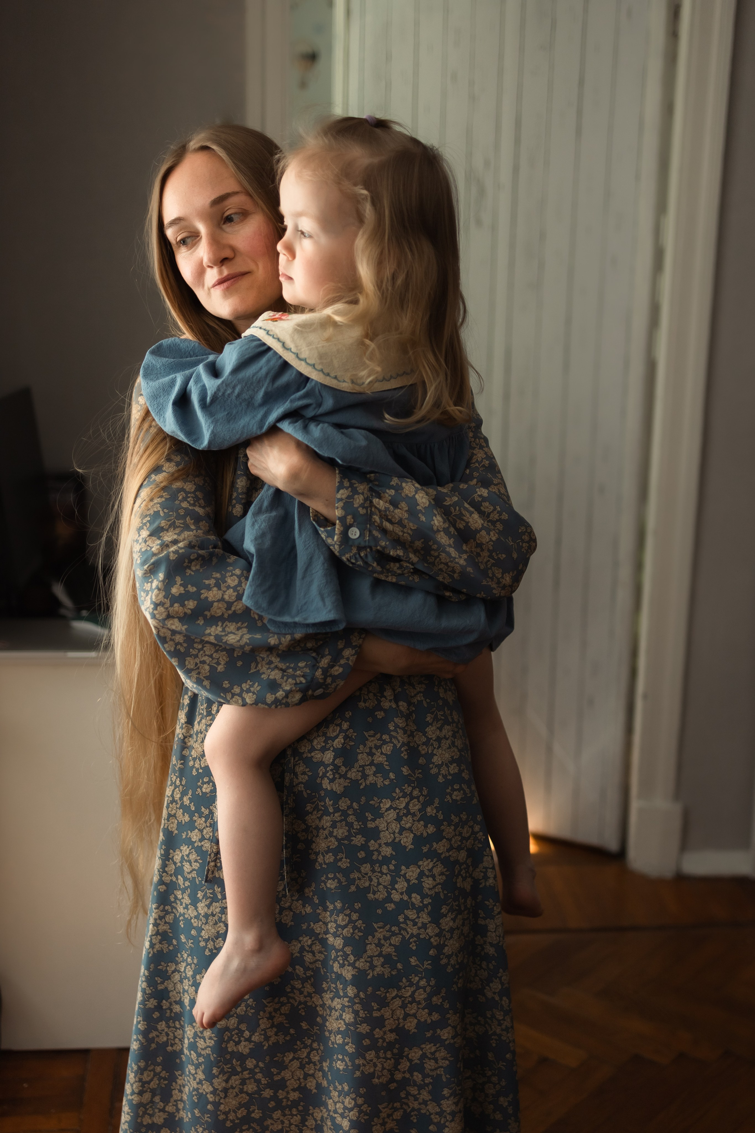 Дочь крепко прижимаются к груди мамы, мягкие волосы переливаются в солнечных лучах