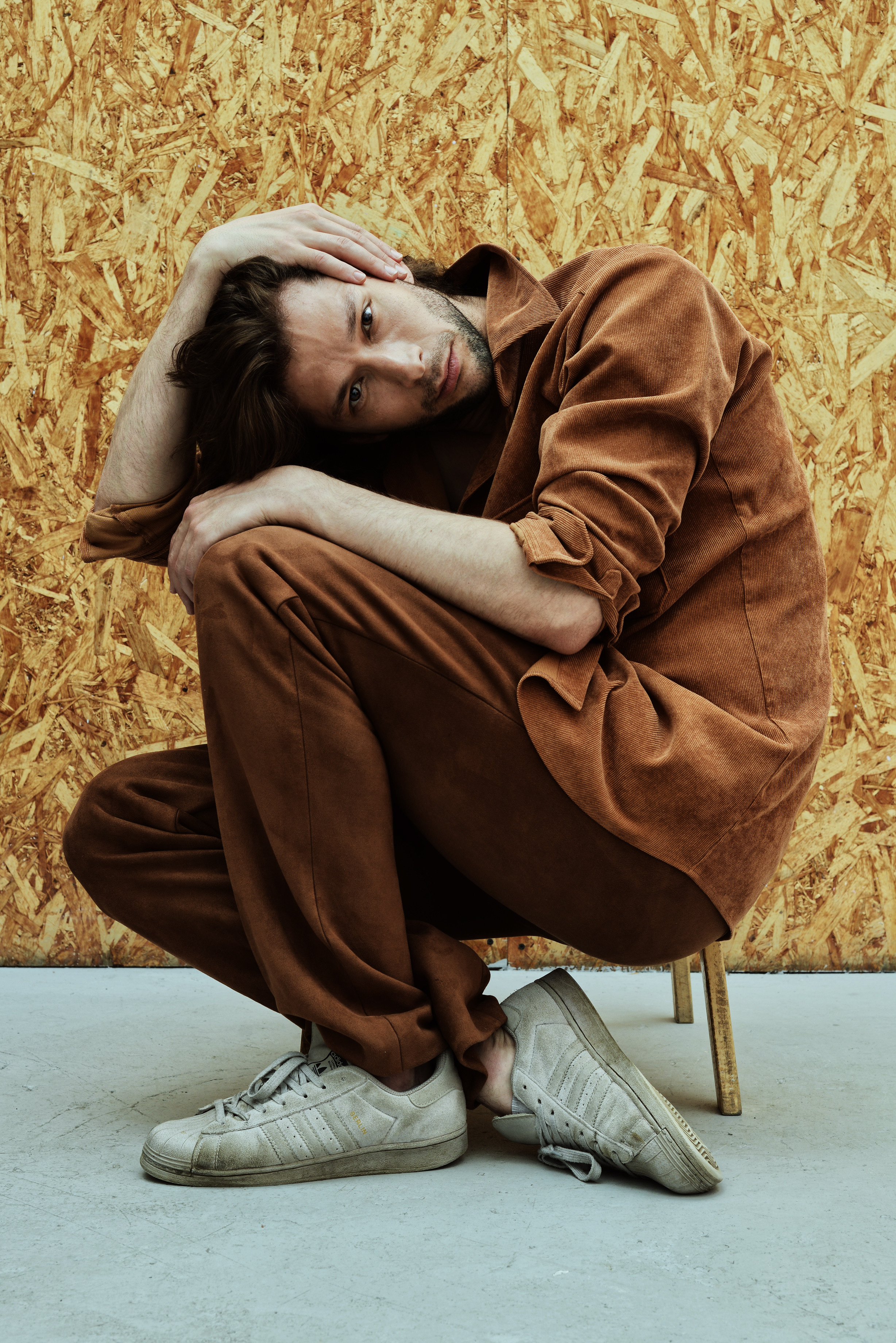 Иван Забелин в студии, мужчина в коричневом костюме сидит на полу