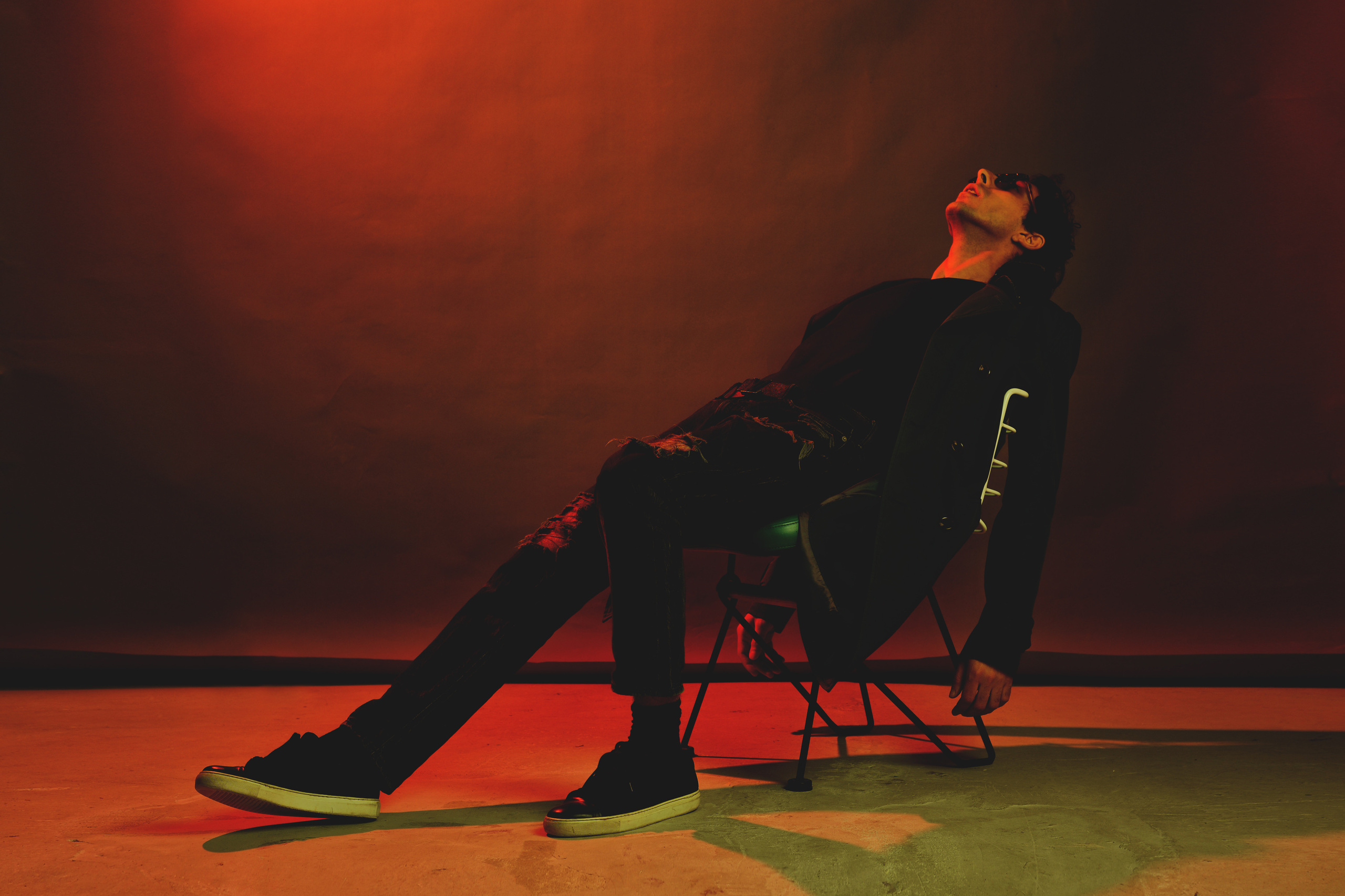 мужчина в пальто сидит на стуле на разноцветном фоне 