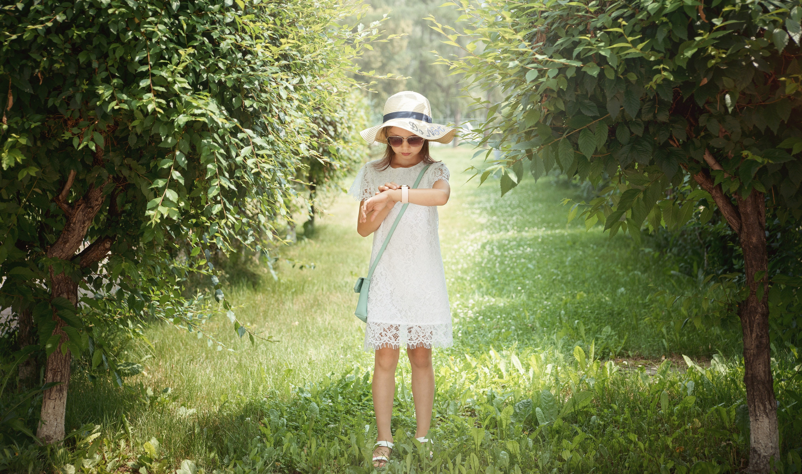 Детская фотосессия летом - девочка стоя смотрит на цветы