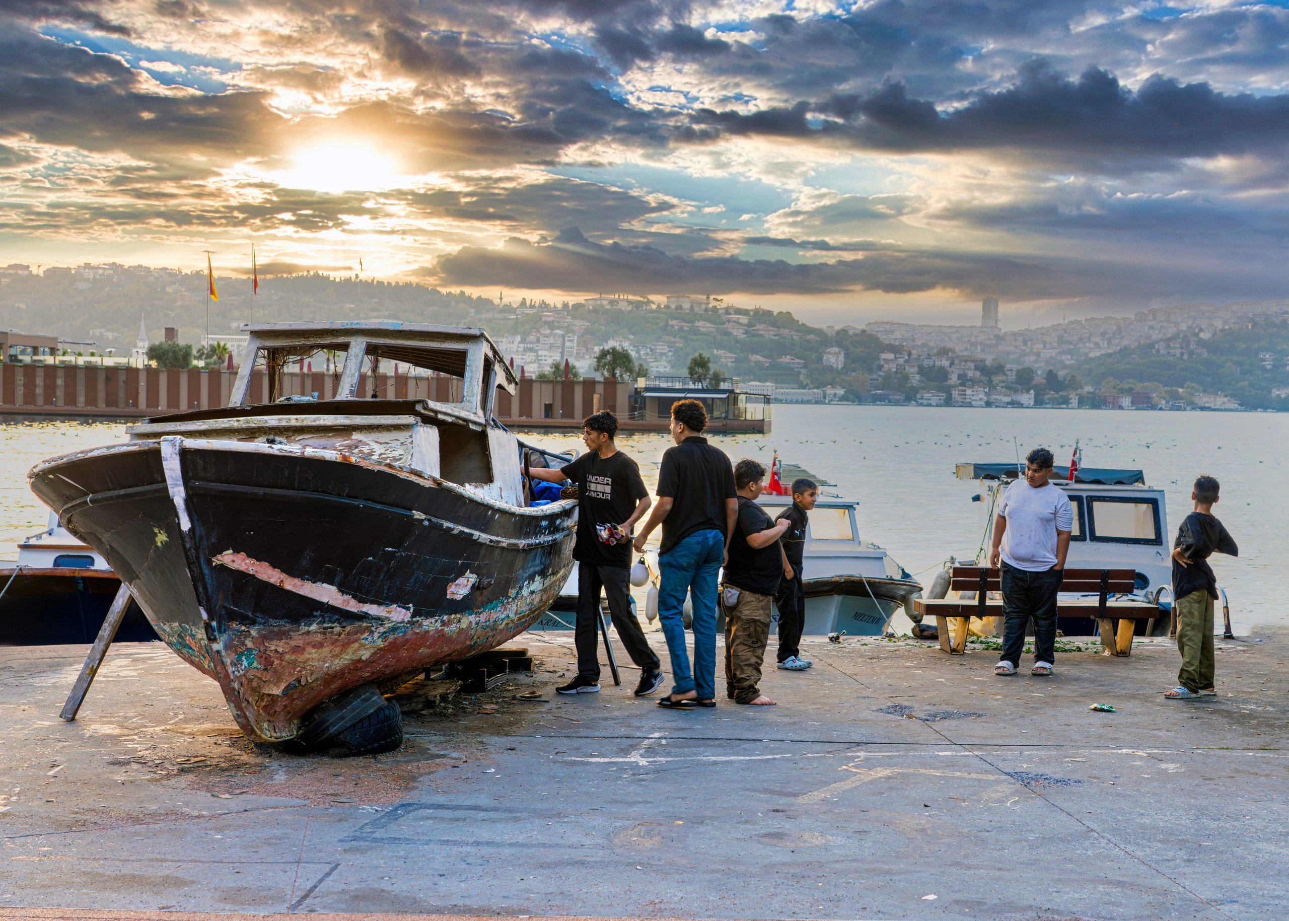 Istanbul waterfront in the early morning, old boat and teenagers, street photography.