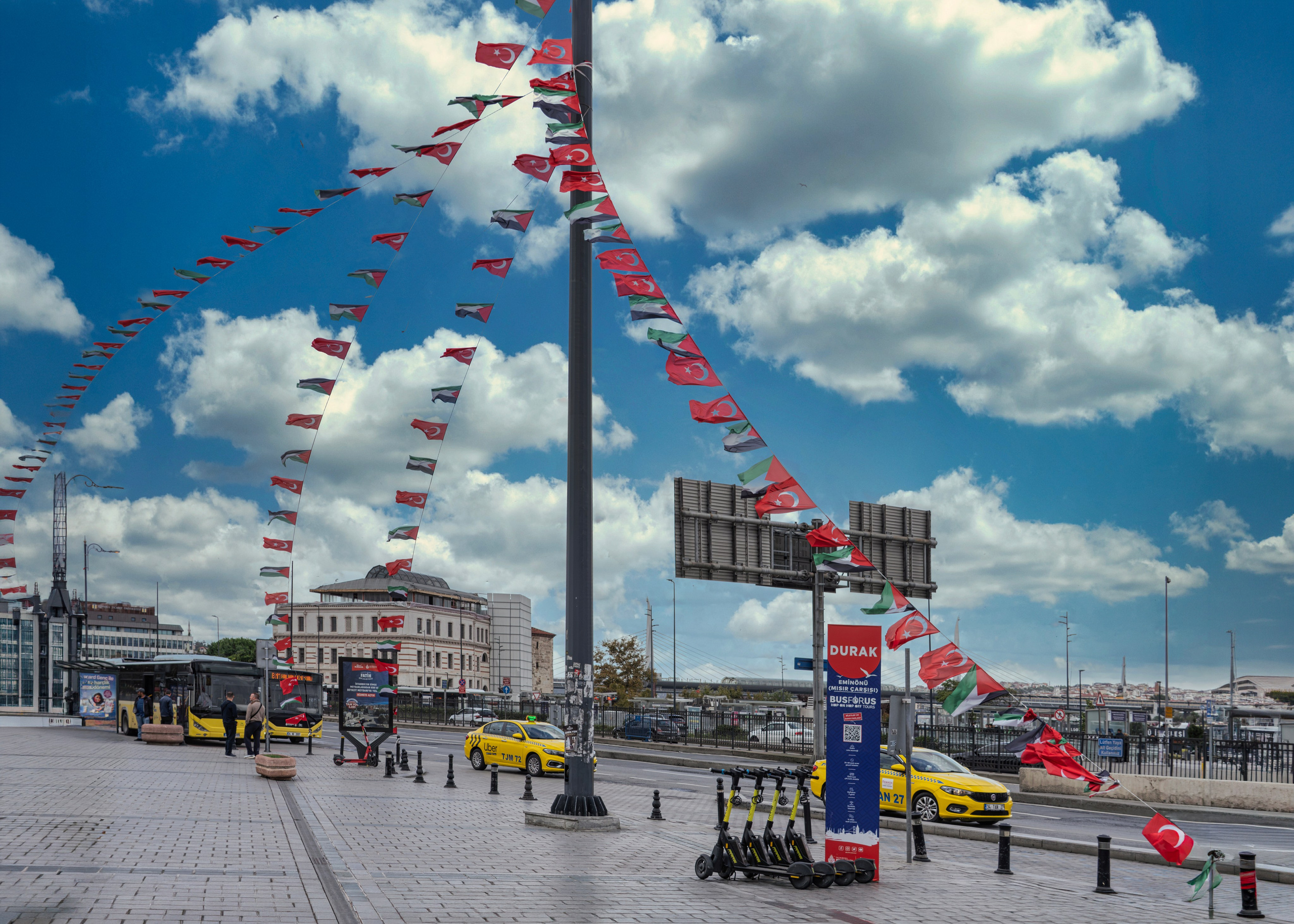 Taksim Square in Istanbul, Turkish flags, yellow taxis and e-scooters, urban photography.