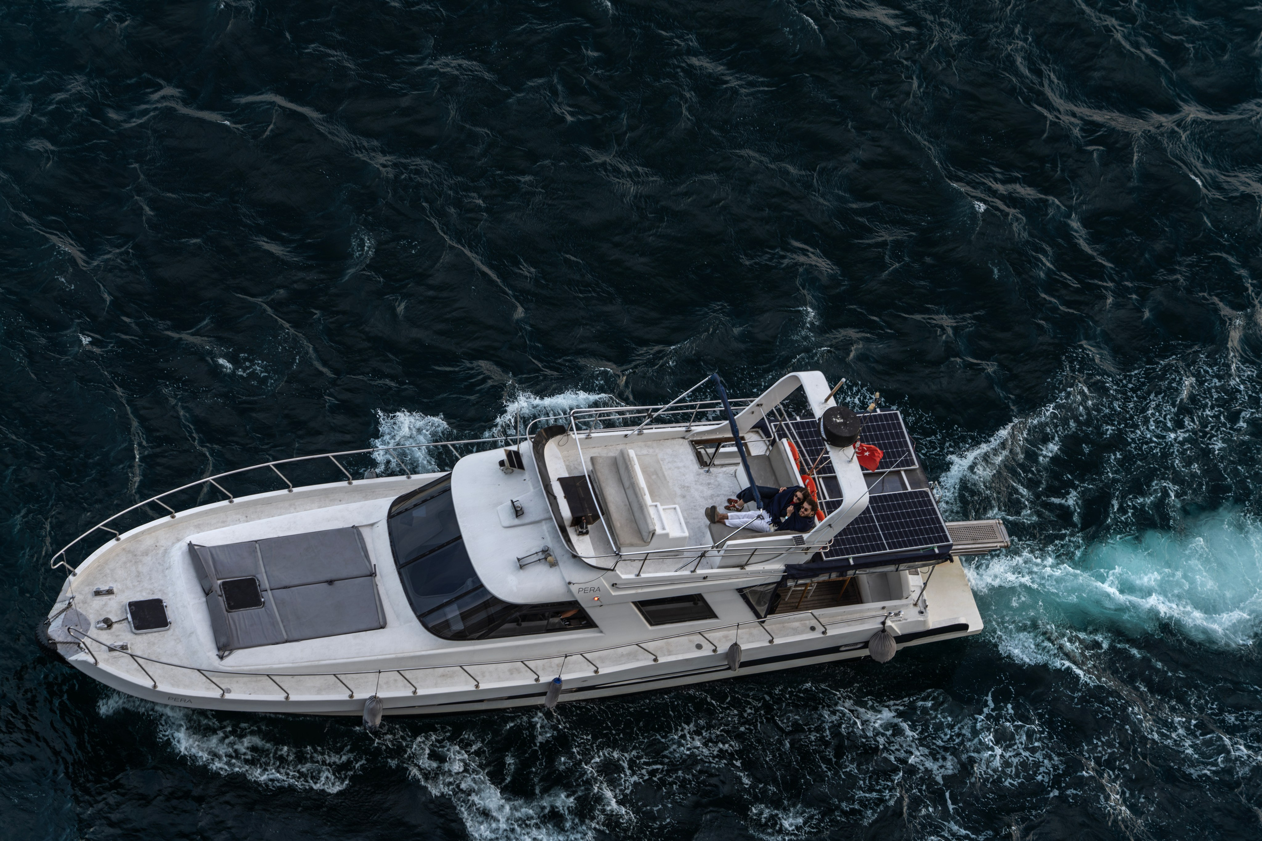 White motor yacht with a Turkish flag on the Bosphorus, top-down view, foamy wake, sea journey, Istanbul.