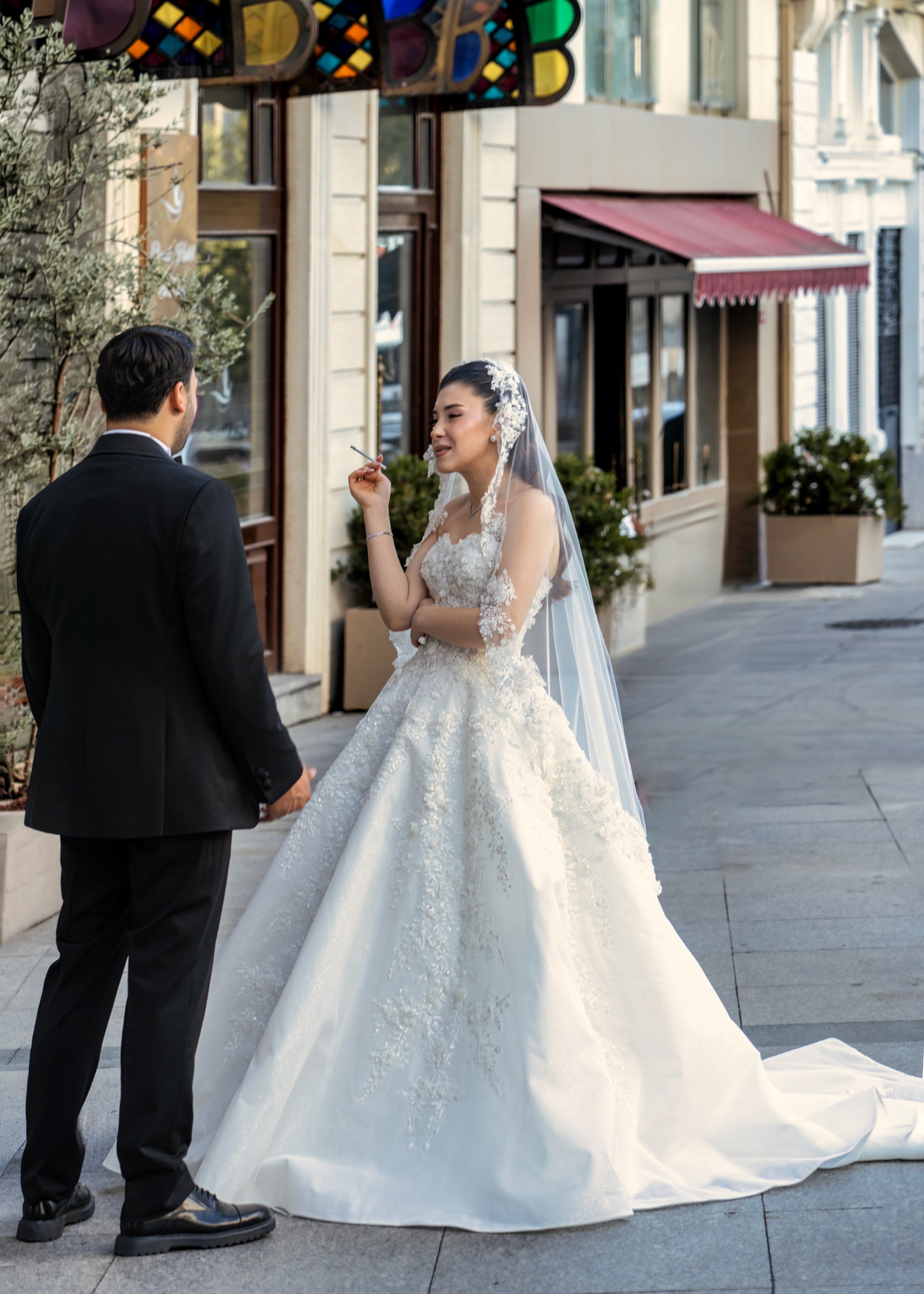 Bride with a cigarette and groom on a street in Istanbul, wedding street photography.
