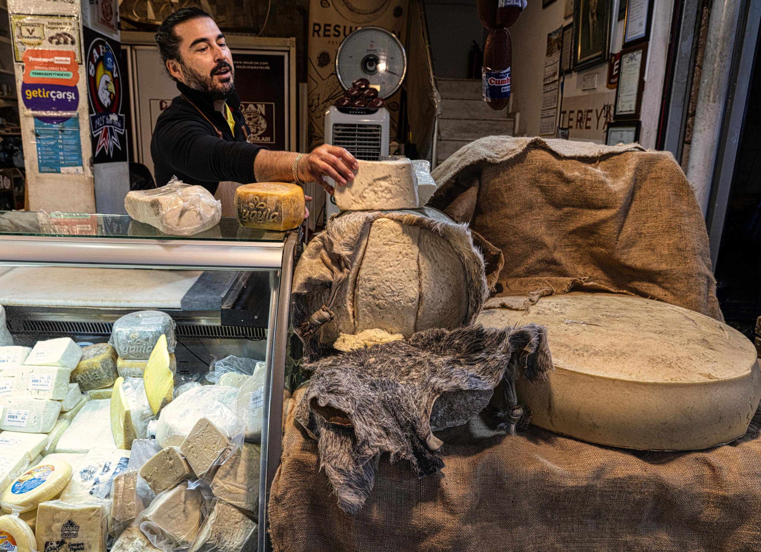 Tulum cheese vendor at a market in Izmir, cheese aged in animal skins, street photography.