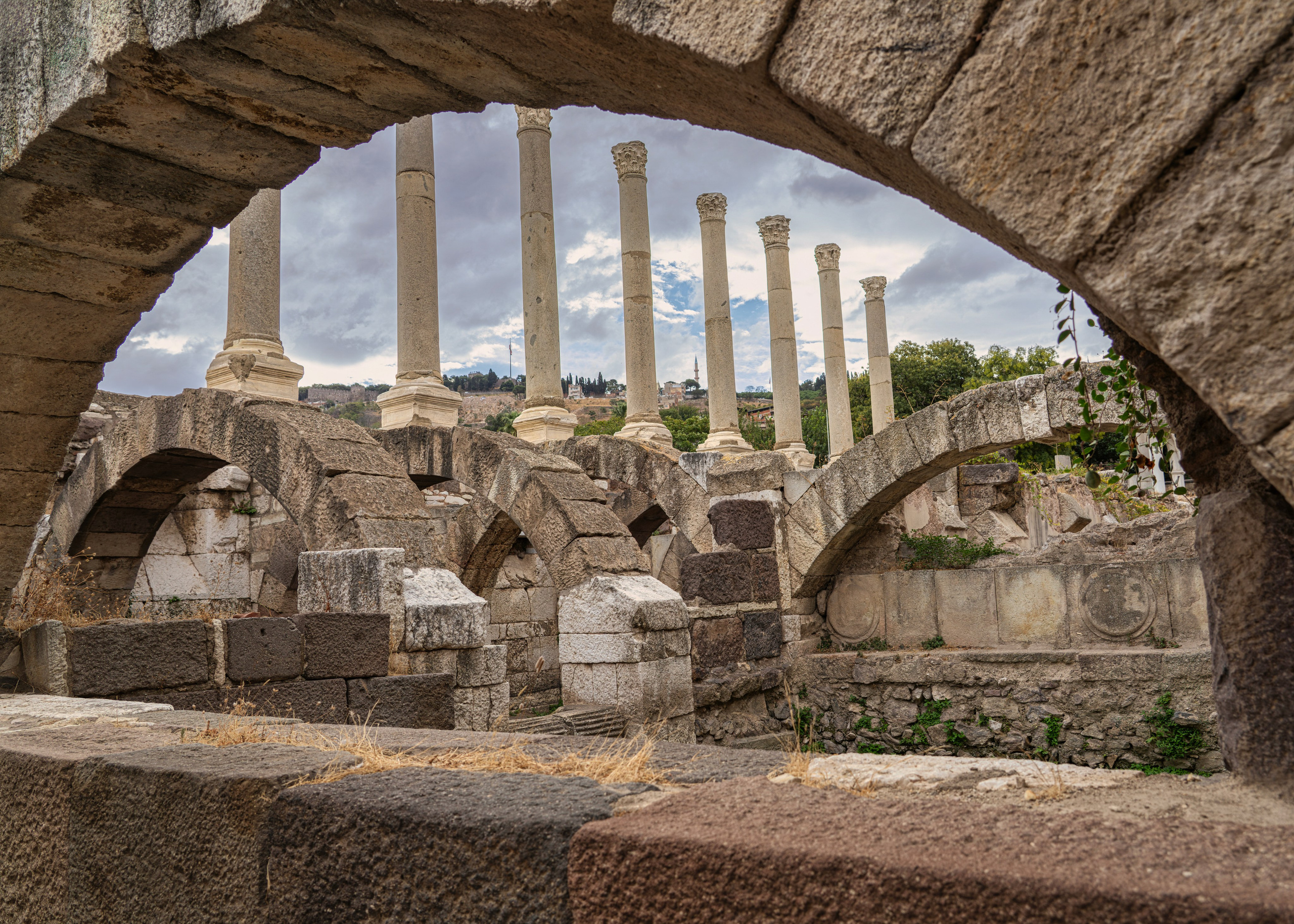 Ancient columns of Smyrna through a stone arch, Kemeraltı market in Izmir, historical photography.