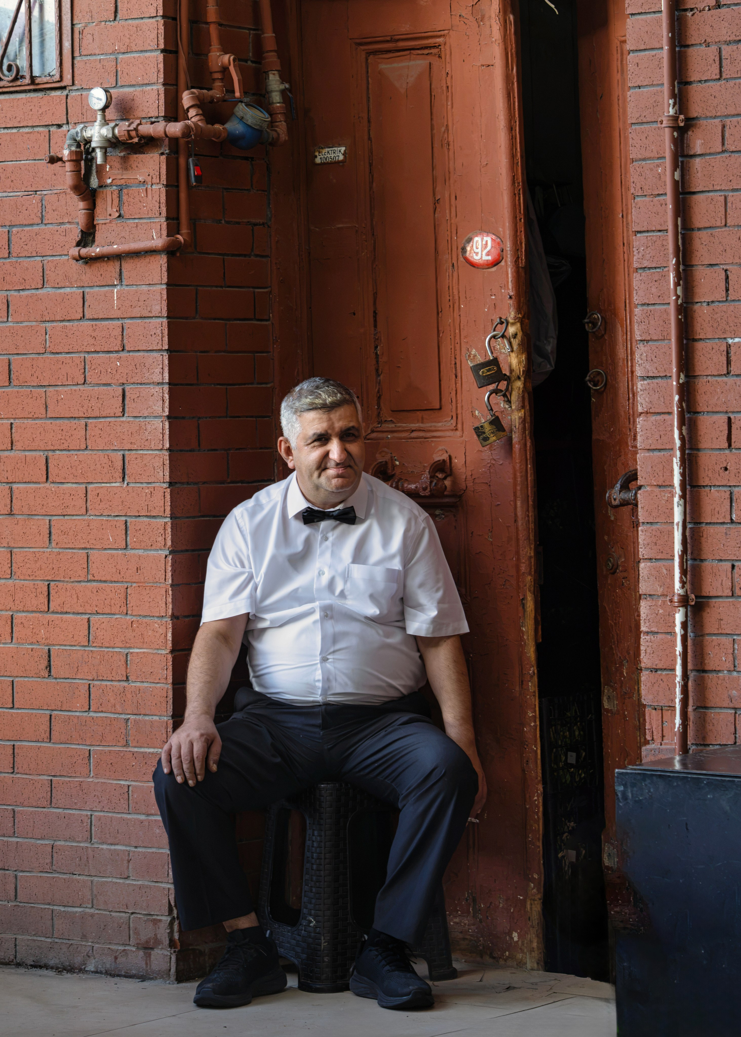 Man in a white shirt and bow tie in front of an old door, Istanbul, street photography.
