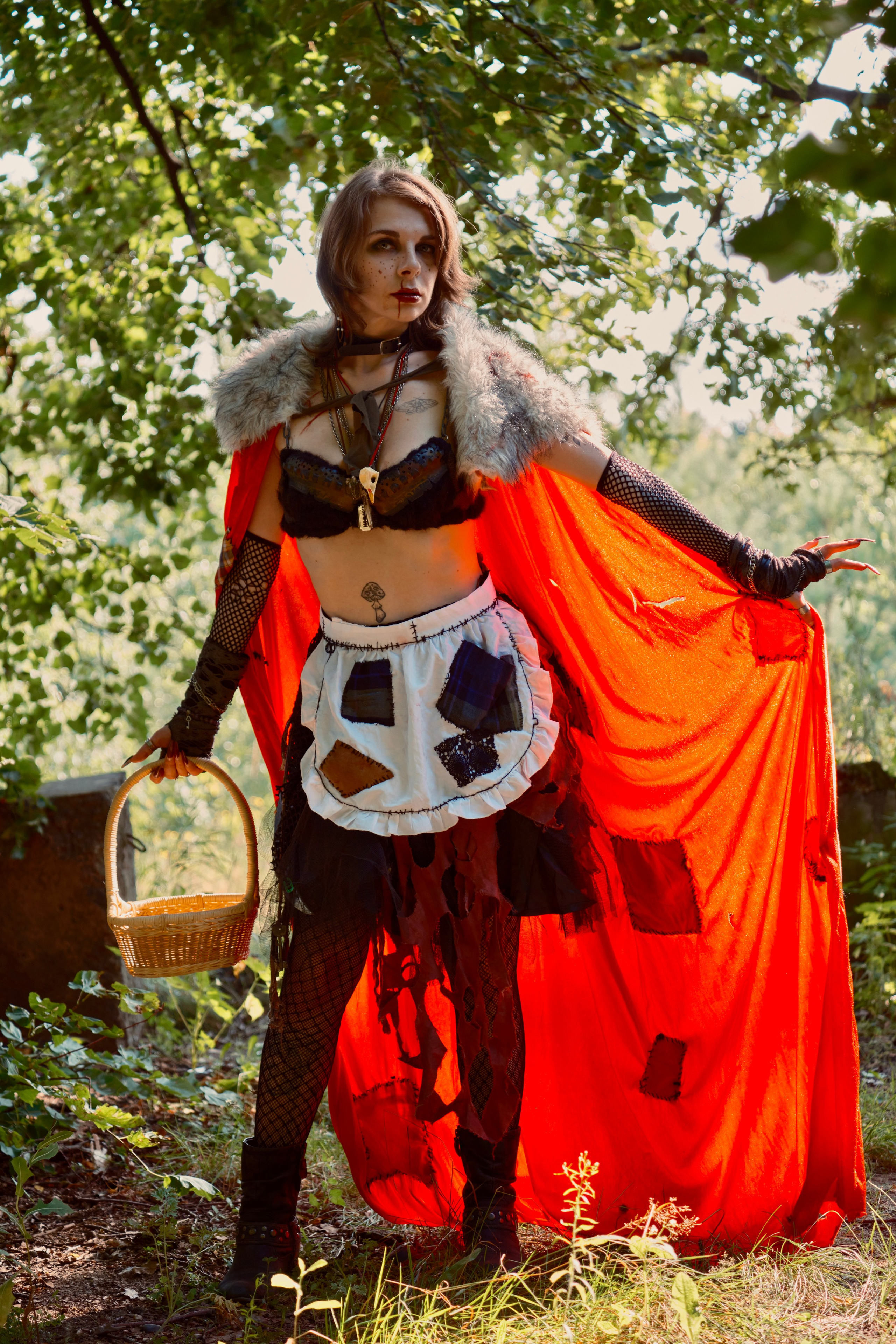 Девушка в красном плаще с корзиночкой гуляет в лесу