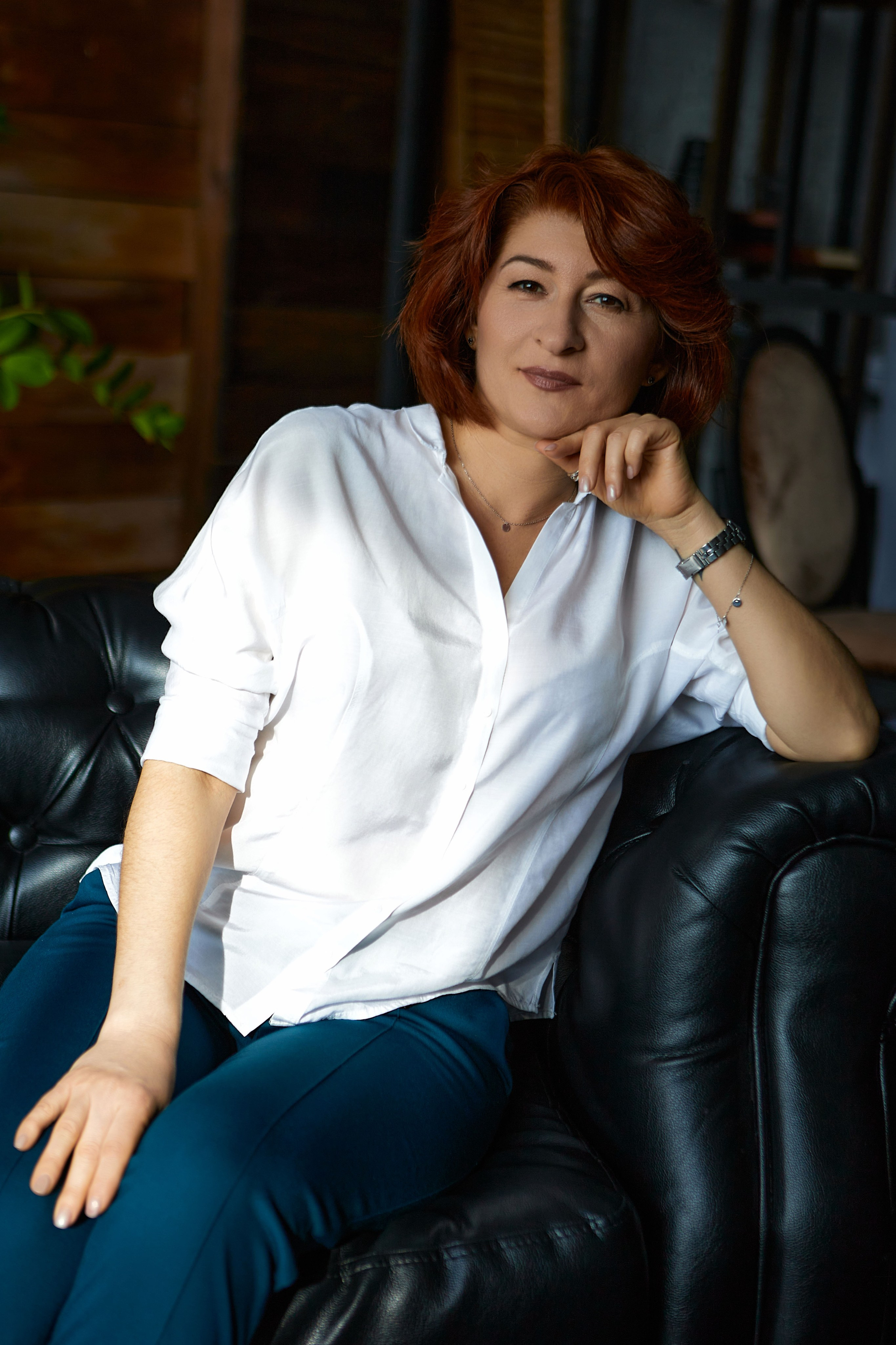 Портрет женщины на кожаном диване на фоне книжного шкафа