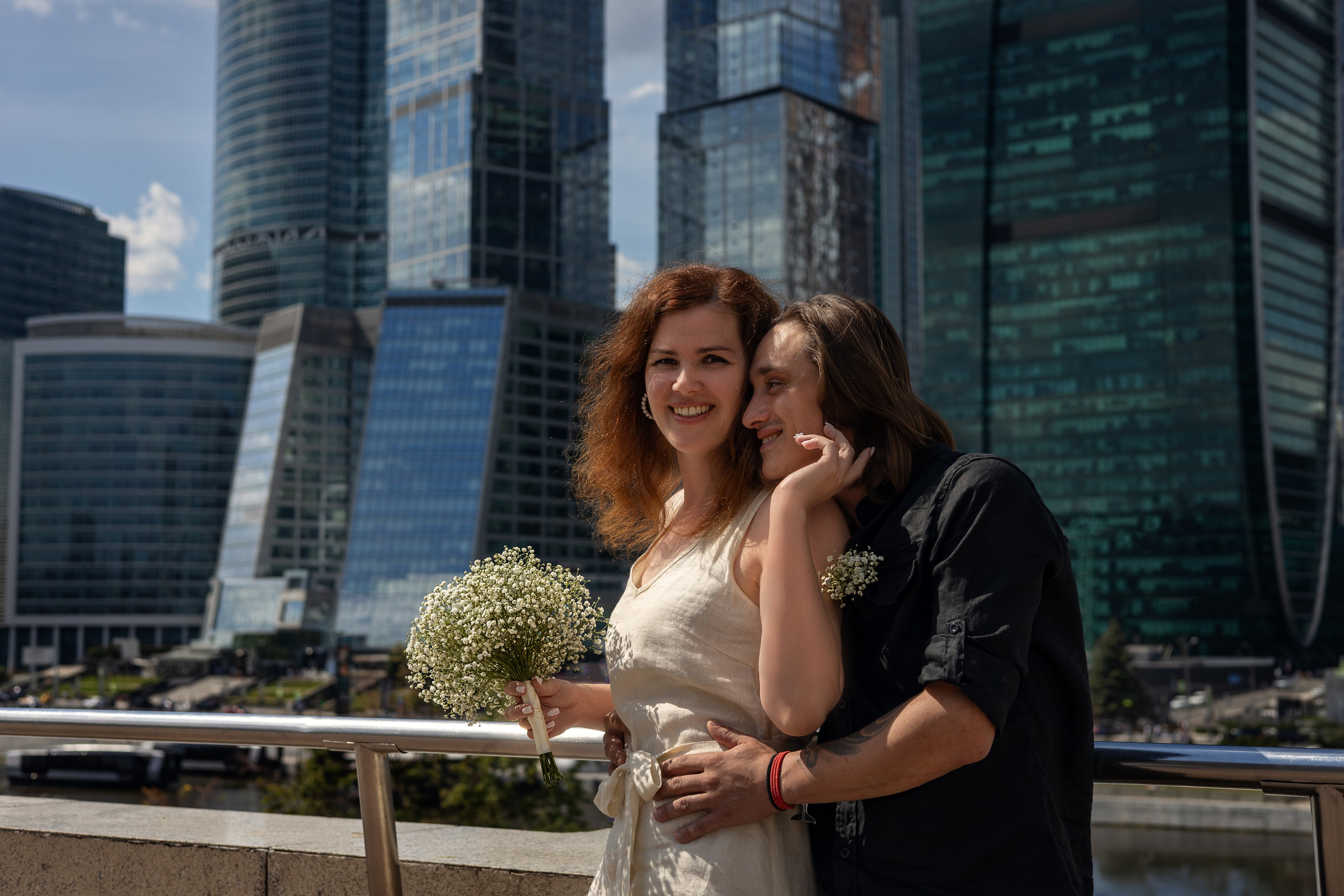 свадебная фотосессия девушка и парень стоят на фоне зданий обнимают друг друга 