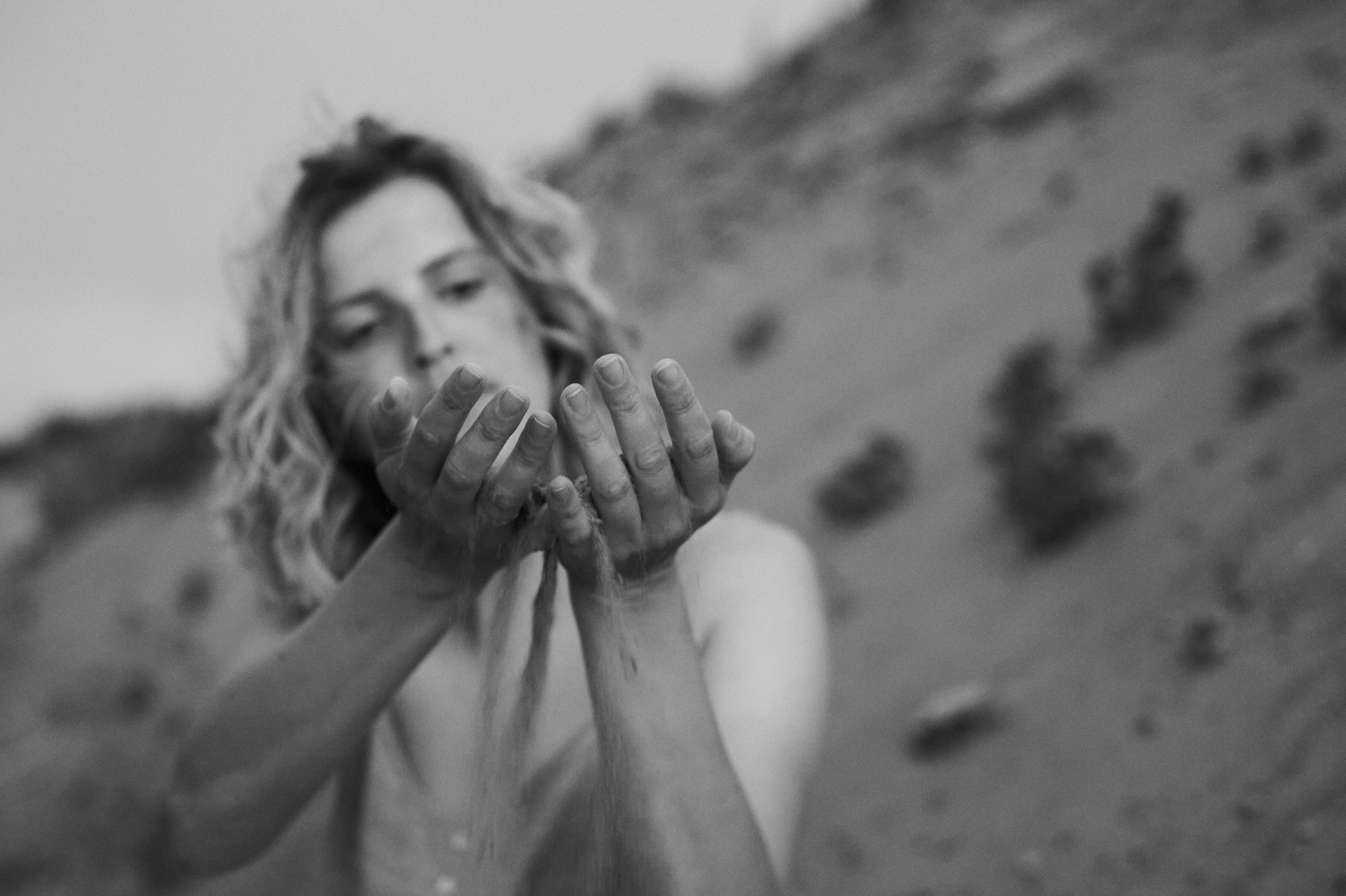 Девушка сыпет песок между пальцами