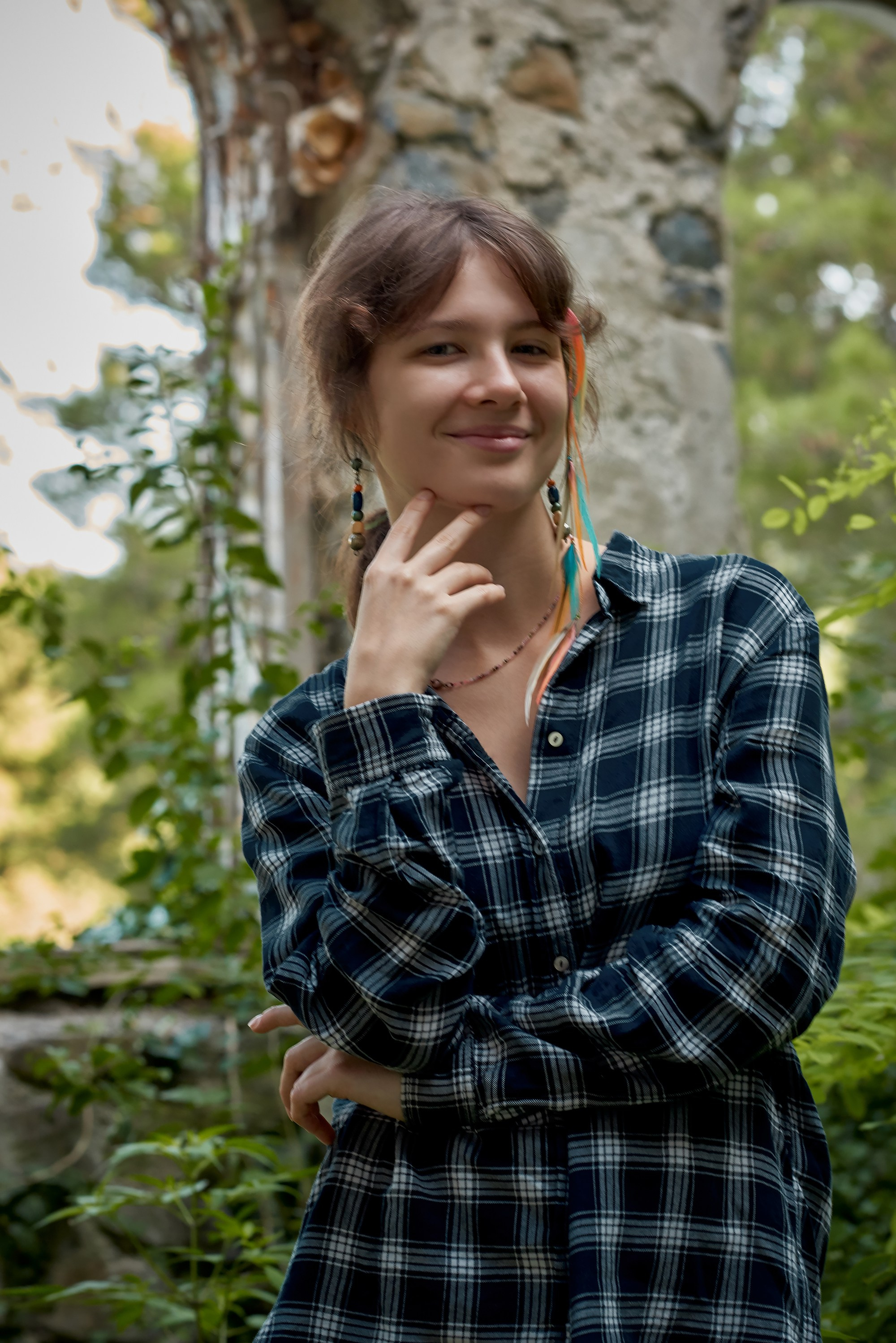 Девушка в синей клетчатой рубашке с длинными рукавами позирует в заброшенном здании