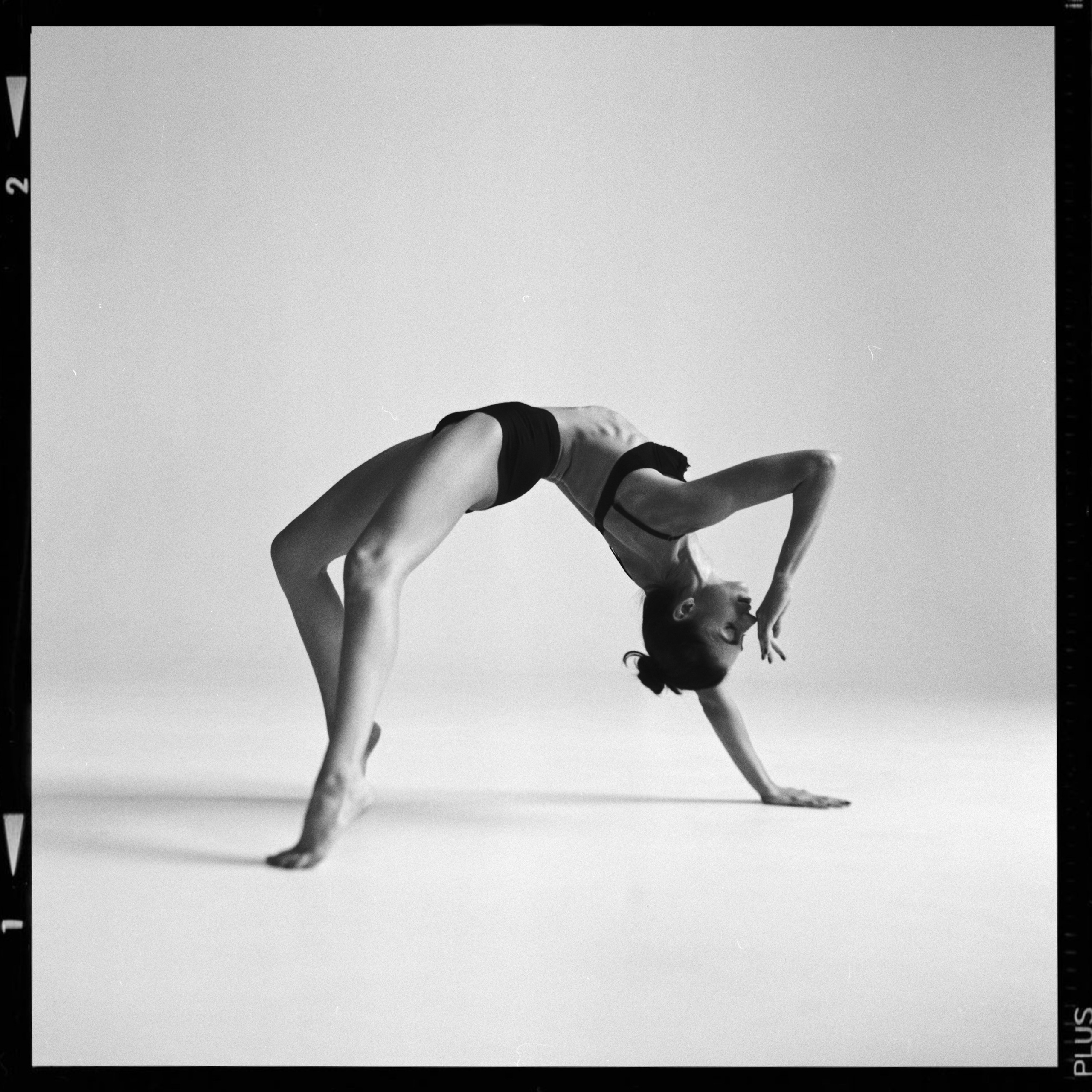 Артистка балета в танцевальной позе красиво стоит на циклораме в фотостудии