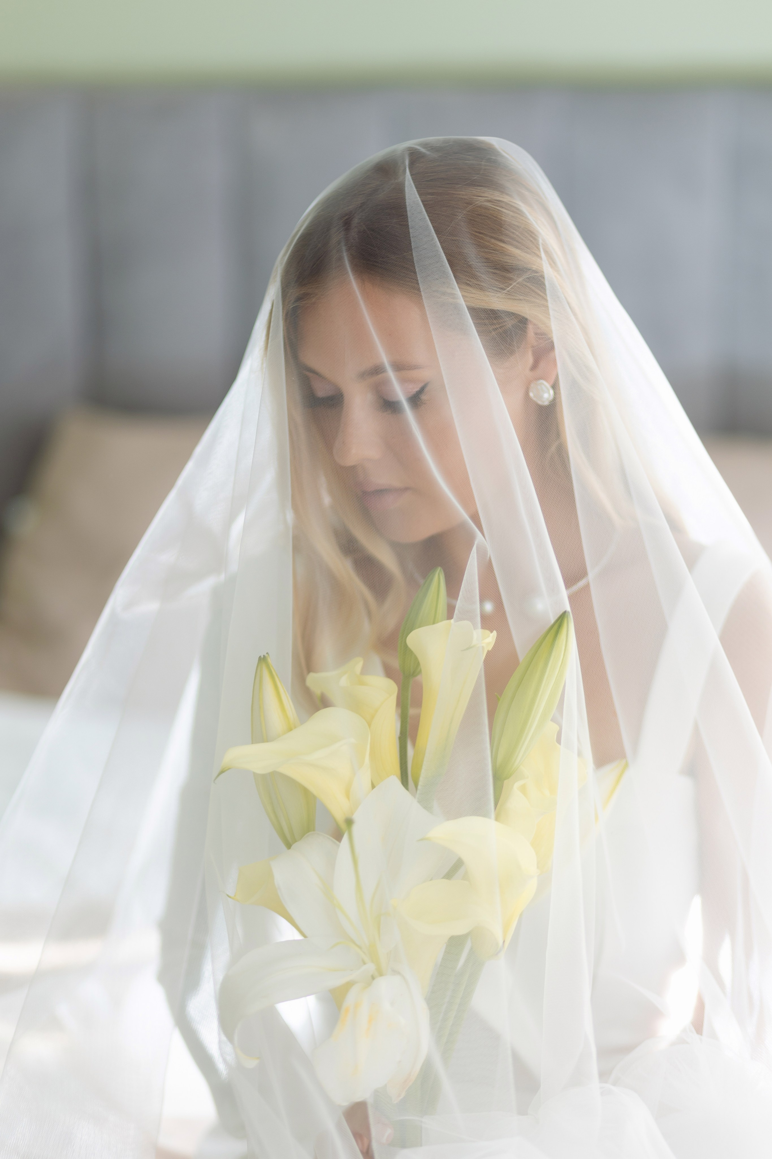 Невеста с букетом покрыта прозрачной вуалью.