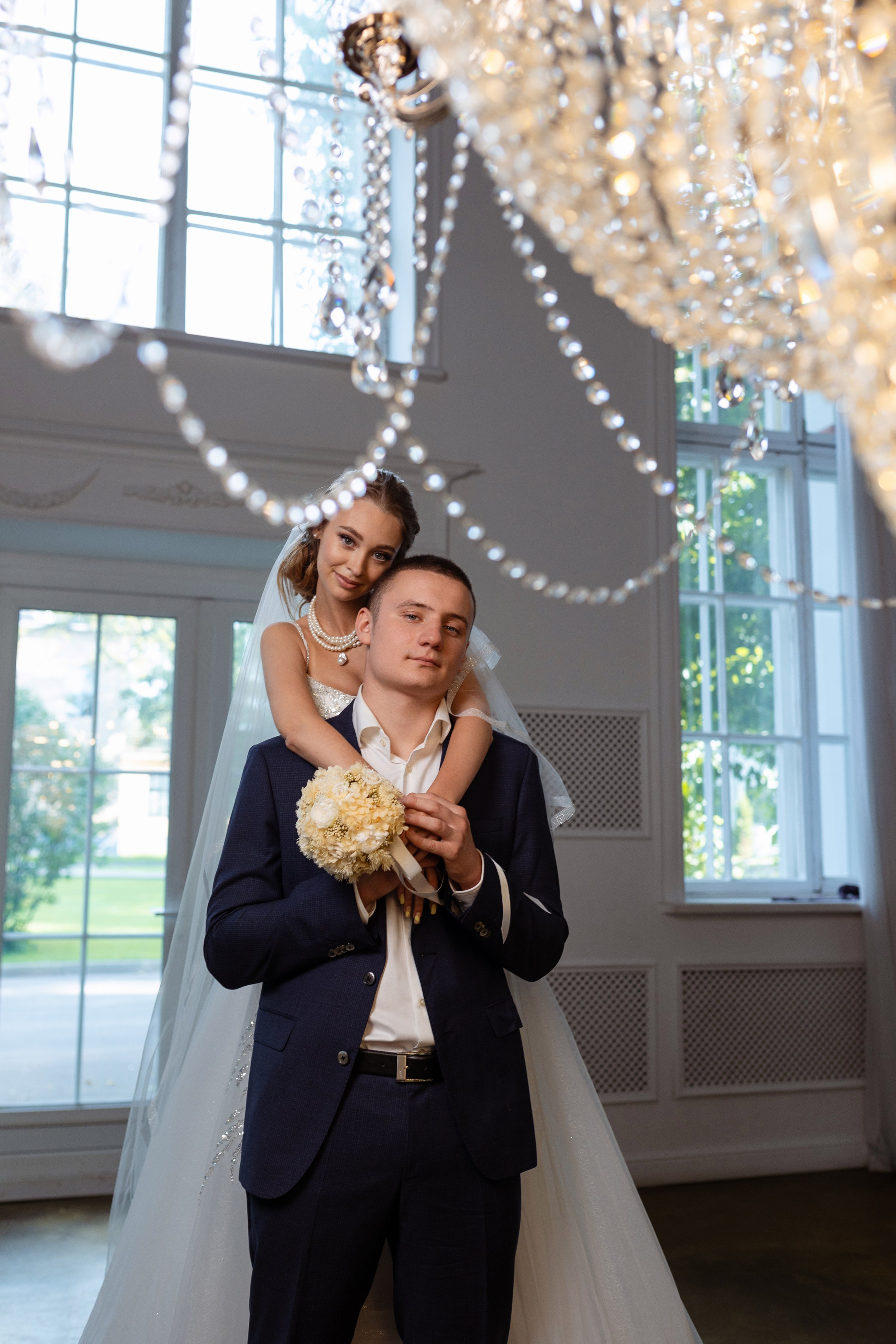 Молодая обняла любимого на фоне больших окон.