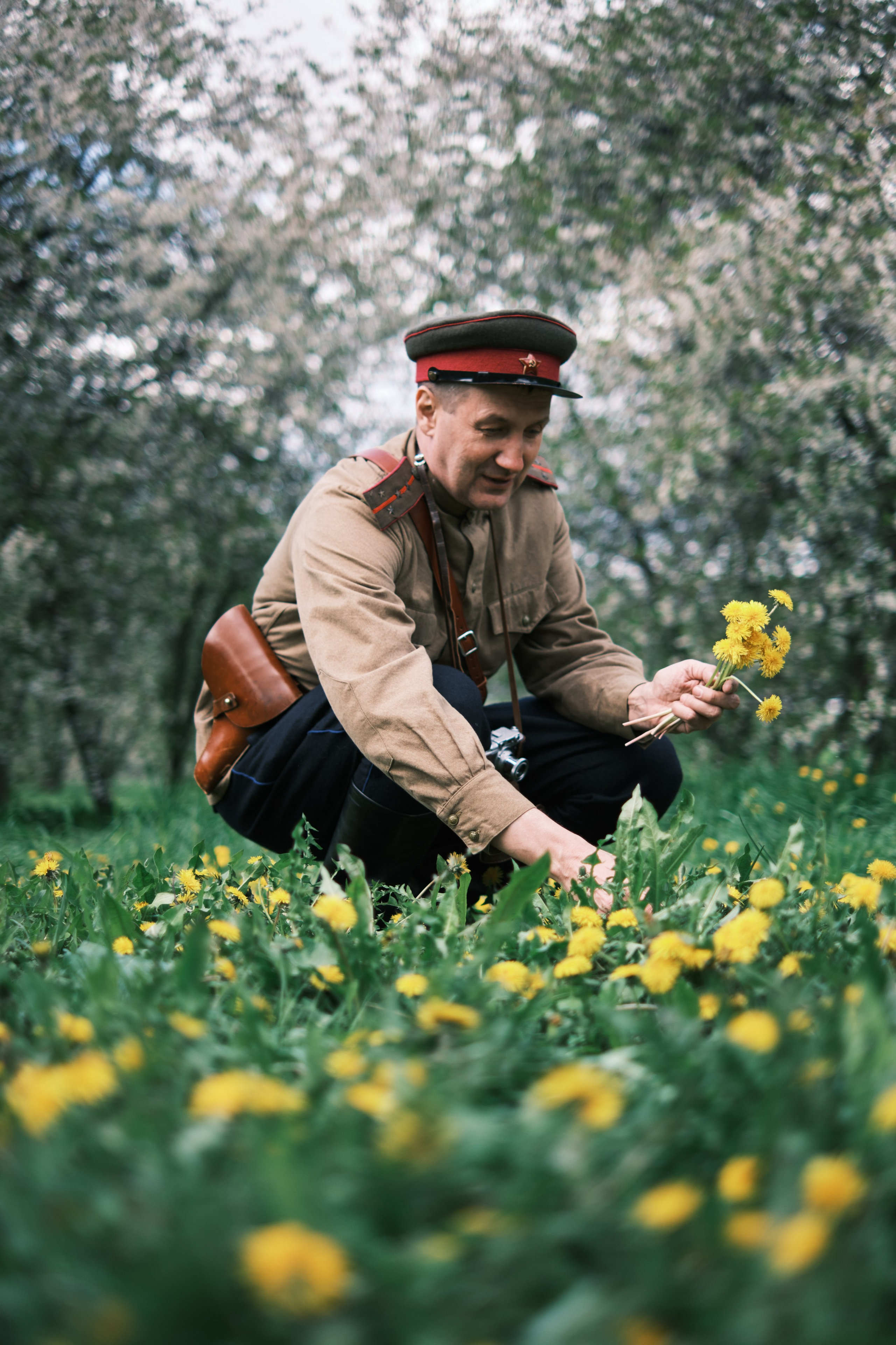 Мужчина в военной форме собирает одуванчики