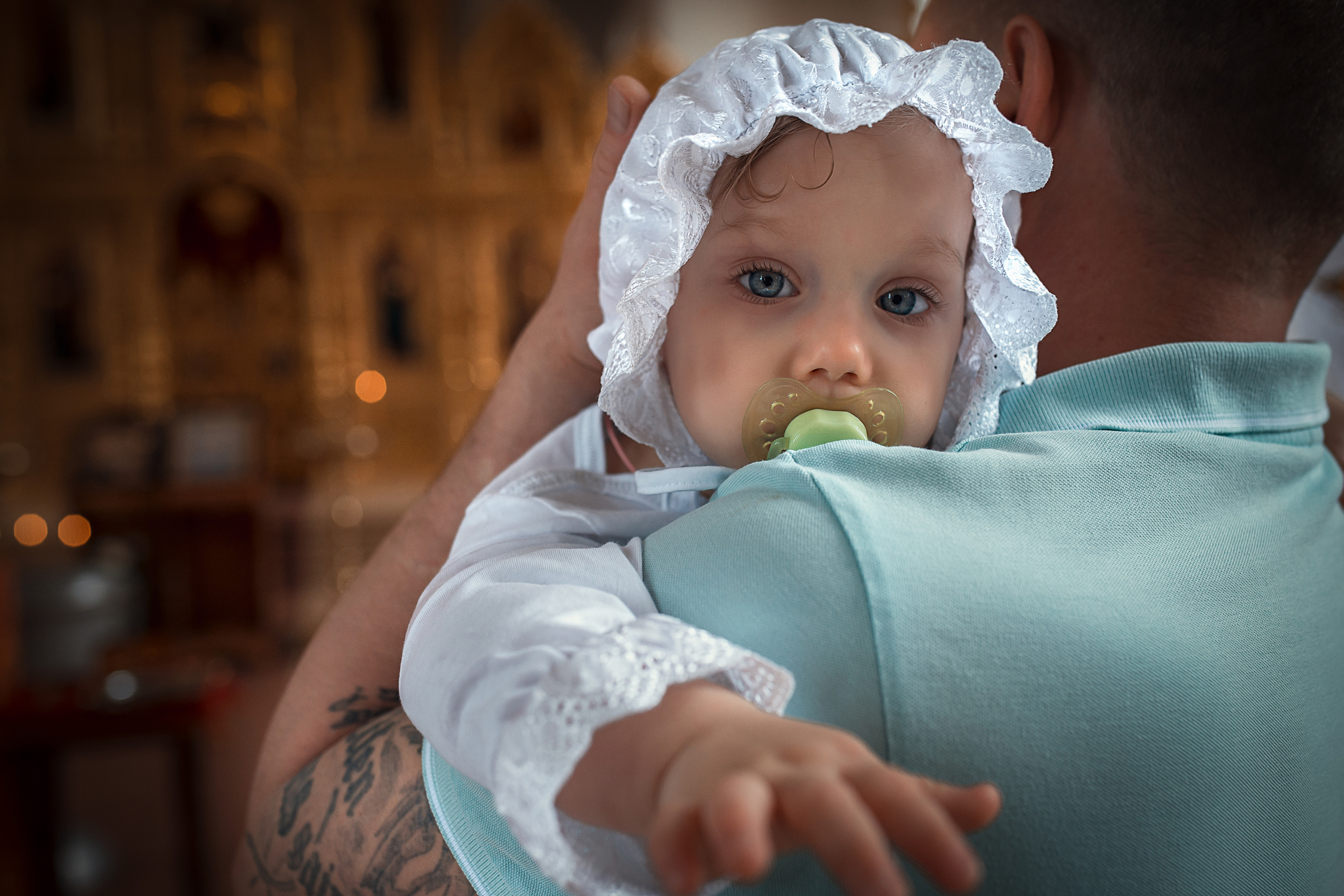 маленькая девочка в крестильной рубашке на руках у папы.