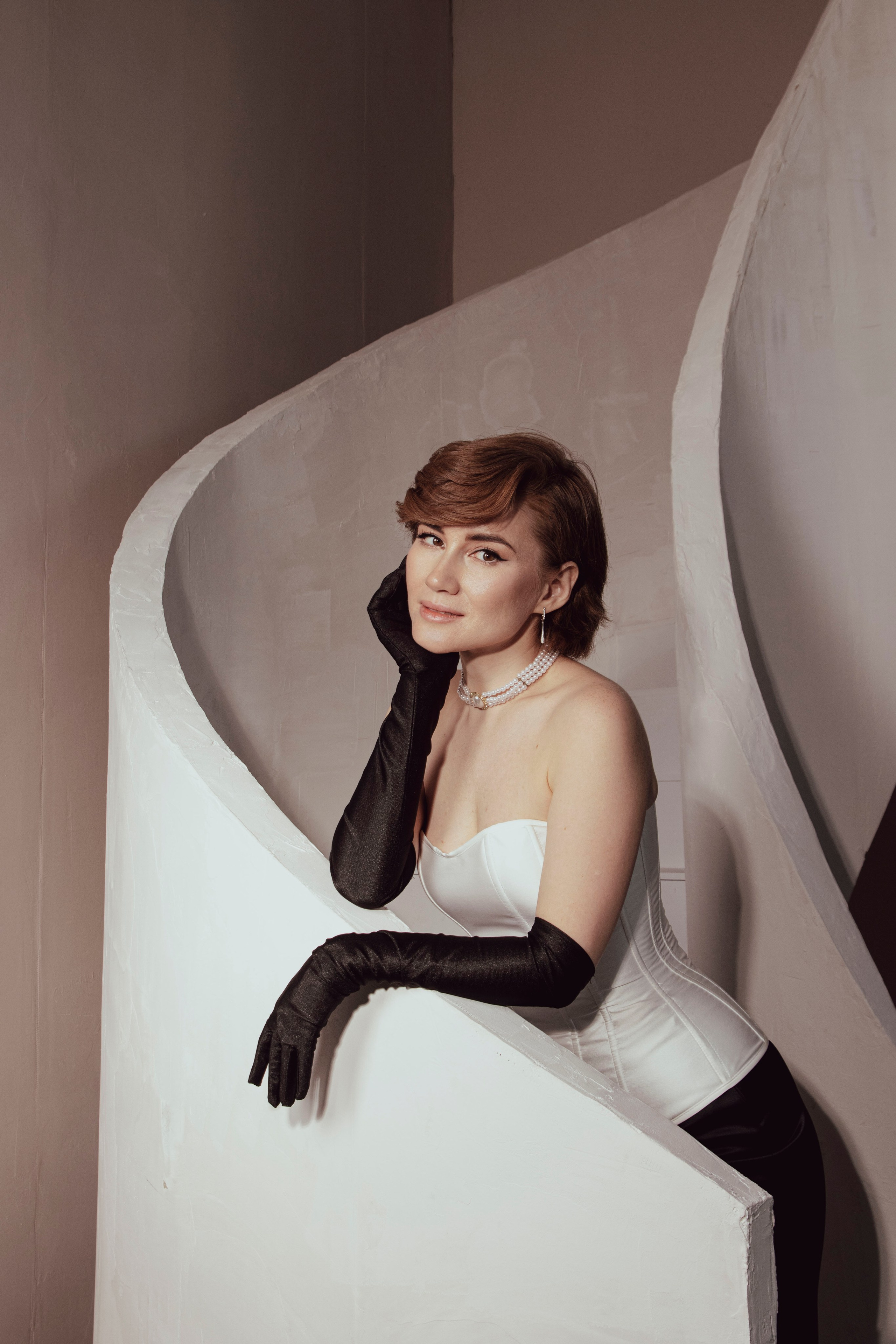 фотосессия девушка в перчатках корсете и юбке облокотилась на перила лестницы