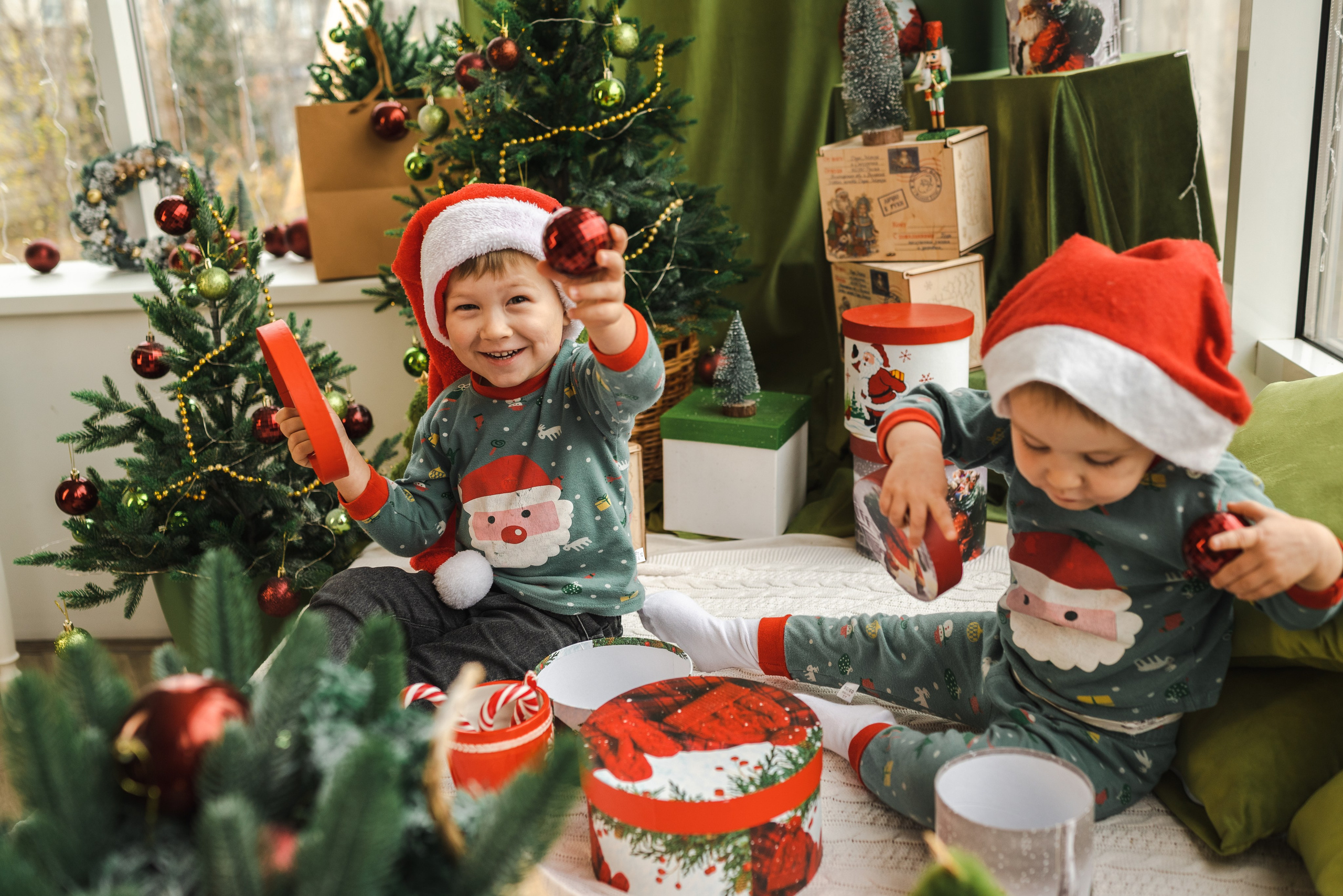 Детская семейная новогодняя фотосессия 2025 в фотостудии в Каменске-Шахтинском и Ростове-на-Дону. Двое маленьких детей сидят на фоне новогодней елки. Фотограф Ольга Сагал 