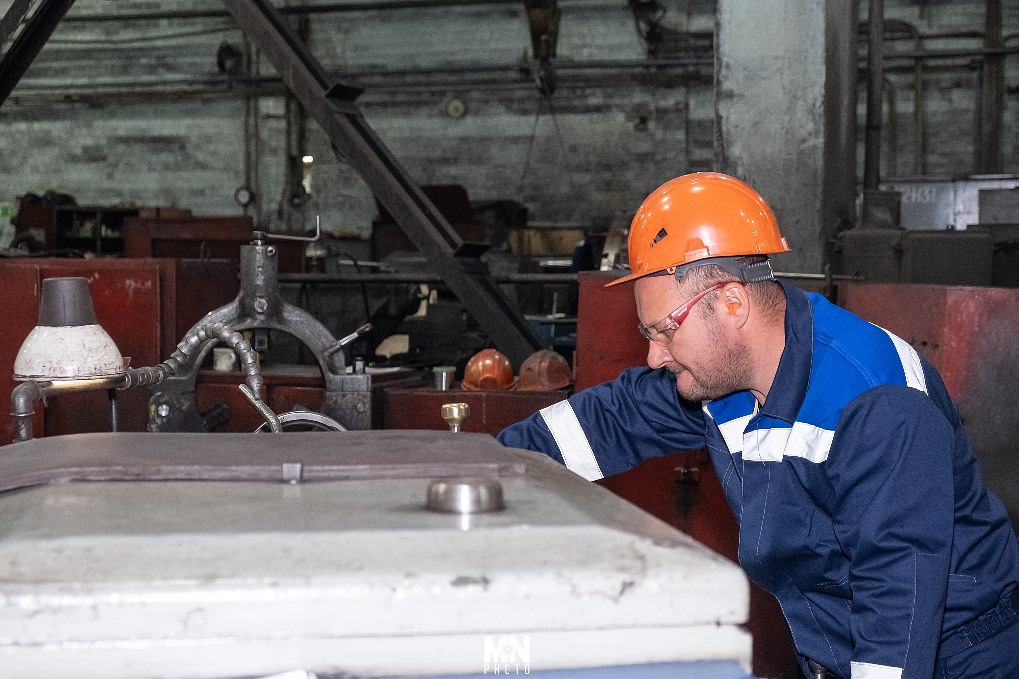 Токарь за работой на станке, производя металлическую деталь. Фотограф Никита Максимов. Междуреченск.