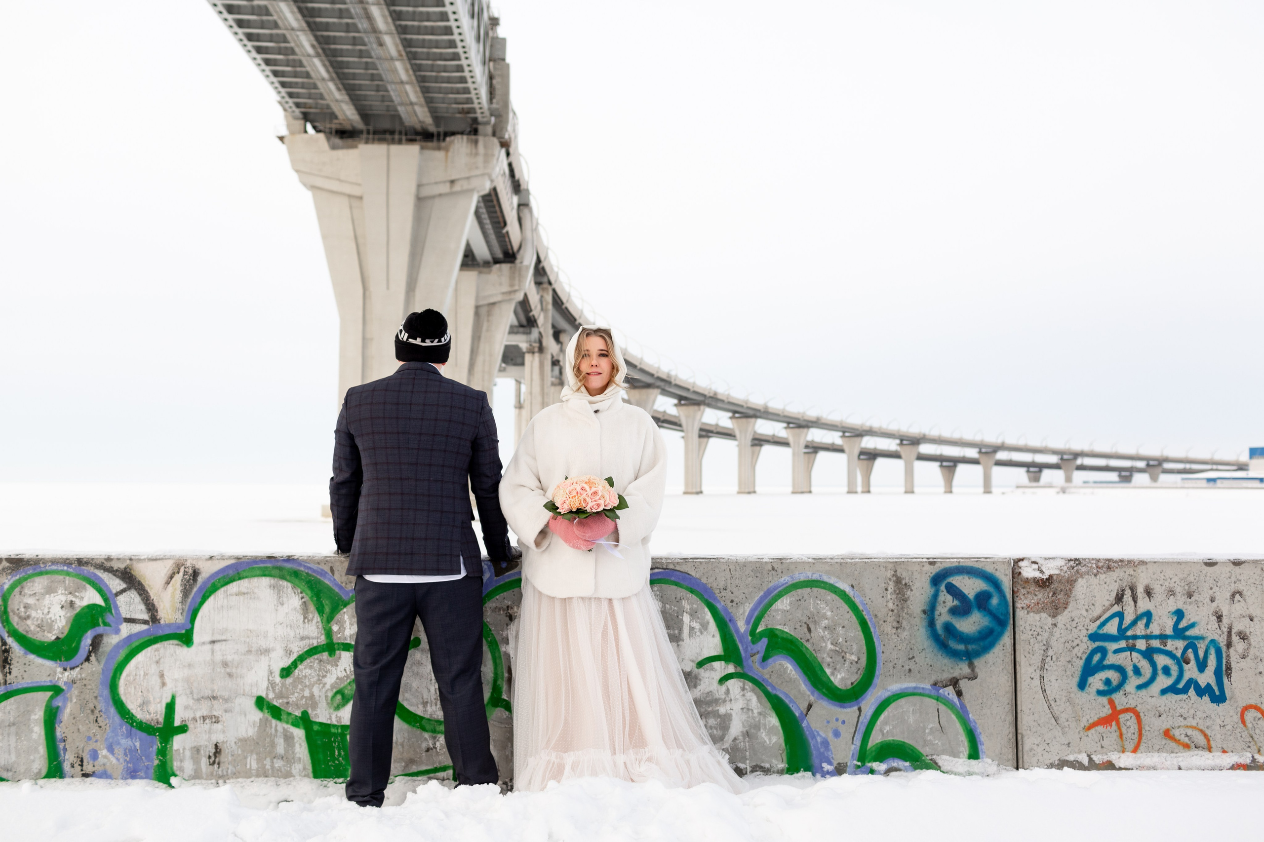 Свадебная фотосессия зимой, невеста в платье и пальто на фоне снега