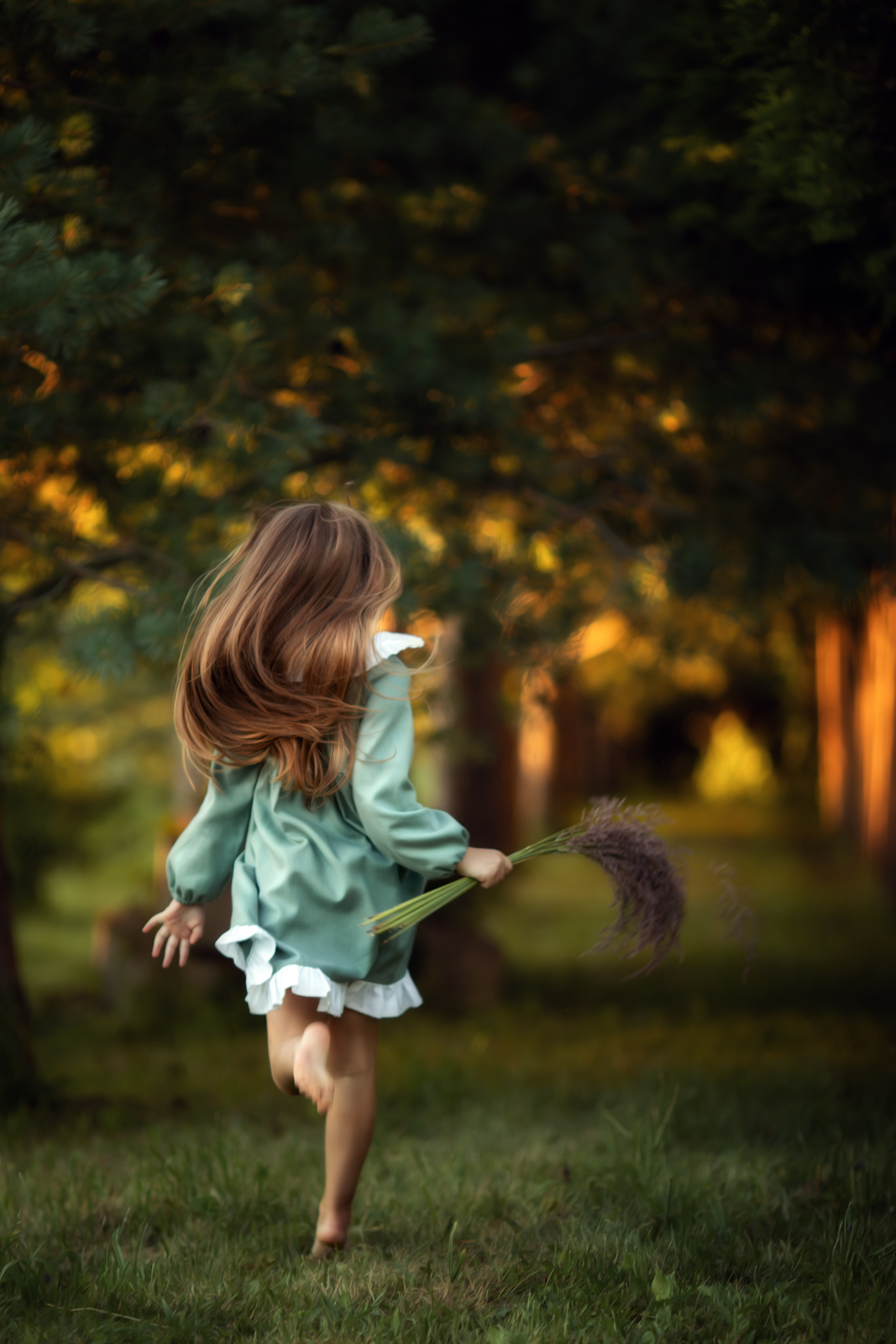 Фото девочки с длинными волосами, бегущей по лесу с букетом трав.