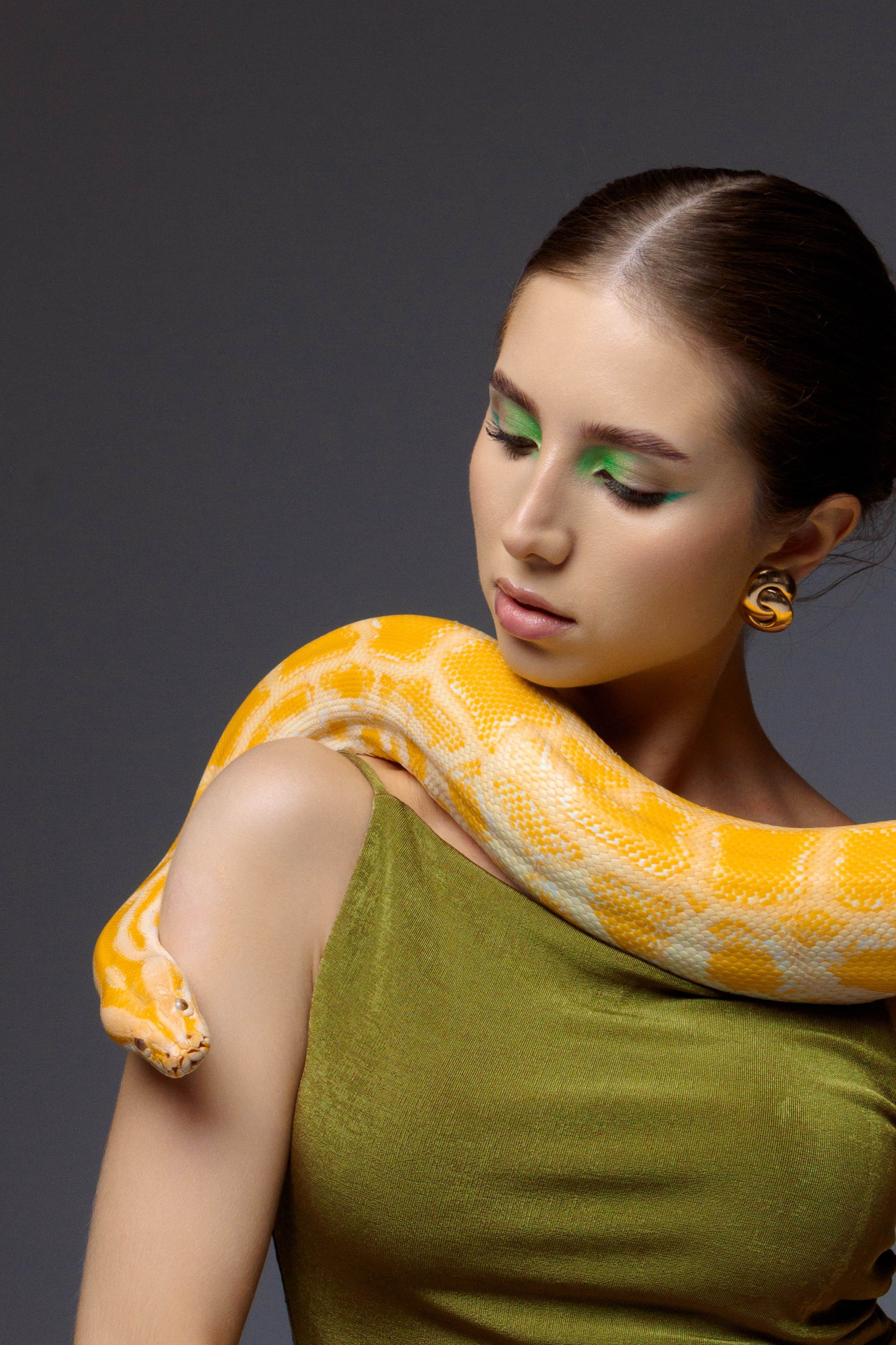 девушка в зеленом платье, на ее шее уютно устроился большой желтый змей (питон)