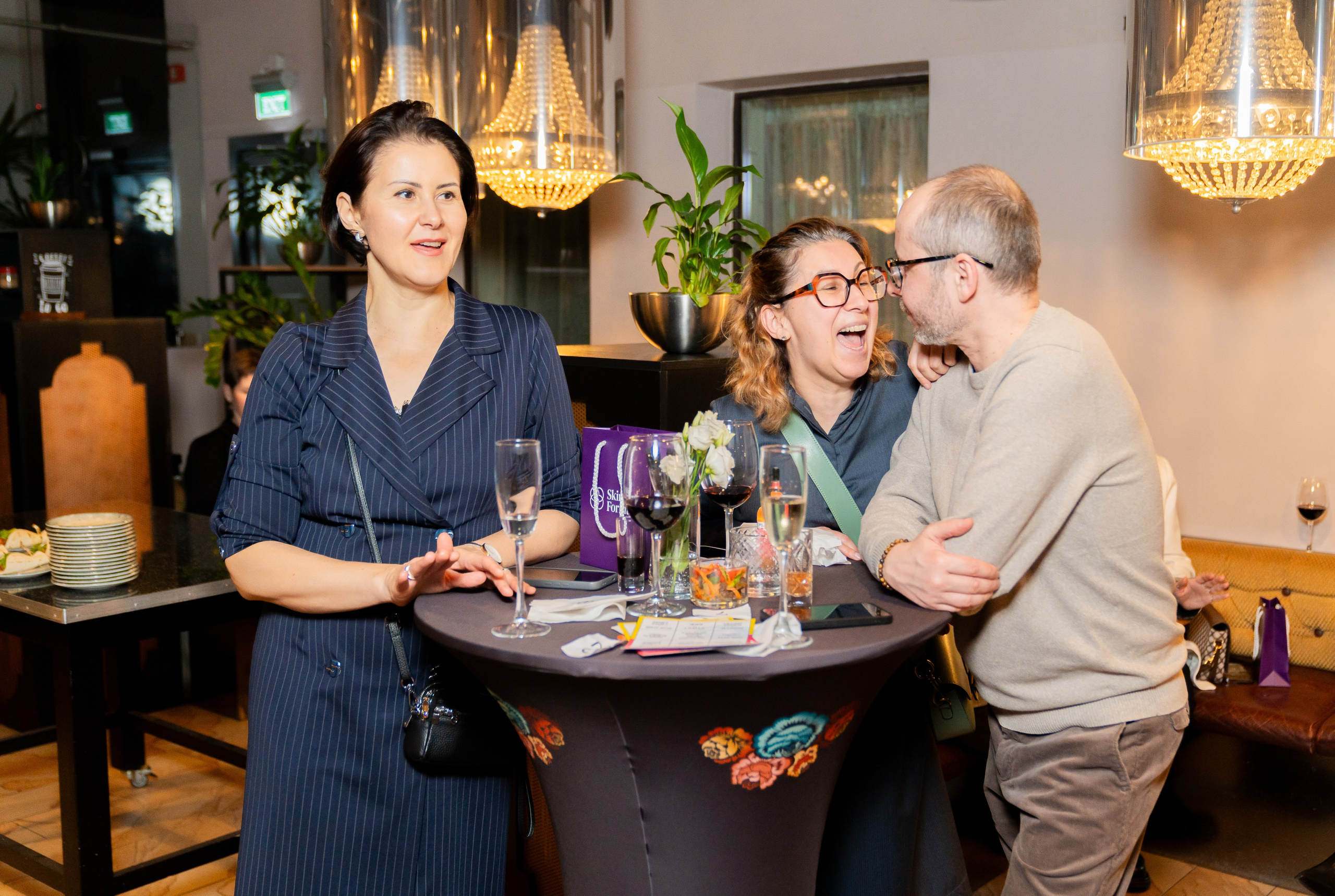 Тёплое общение за столом на мероприятии Radisson Sonya: девушка в полосатом платье, смеющаяся гостья и мужчина в свитере. Фото Евгения Мальцева (evrednix.ru).