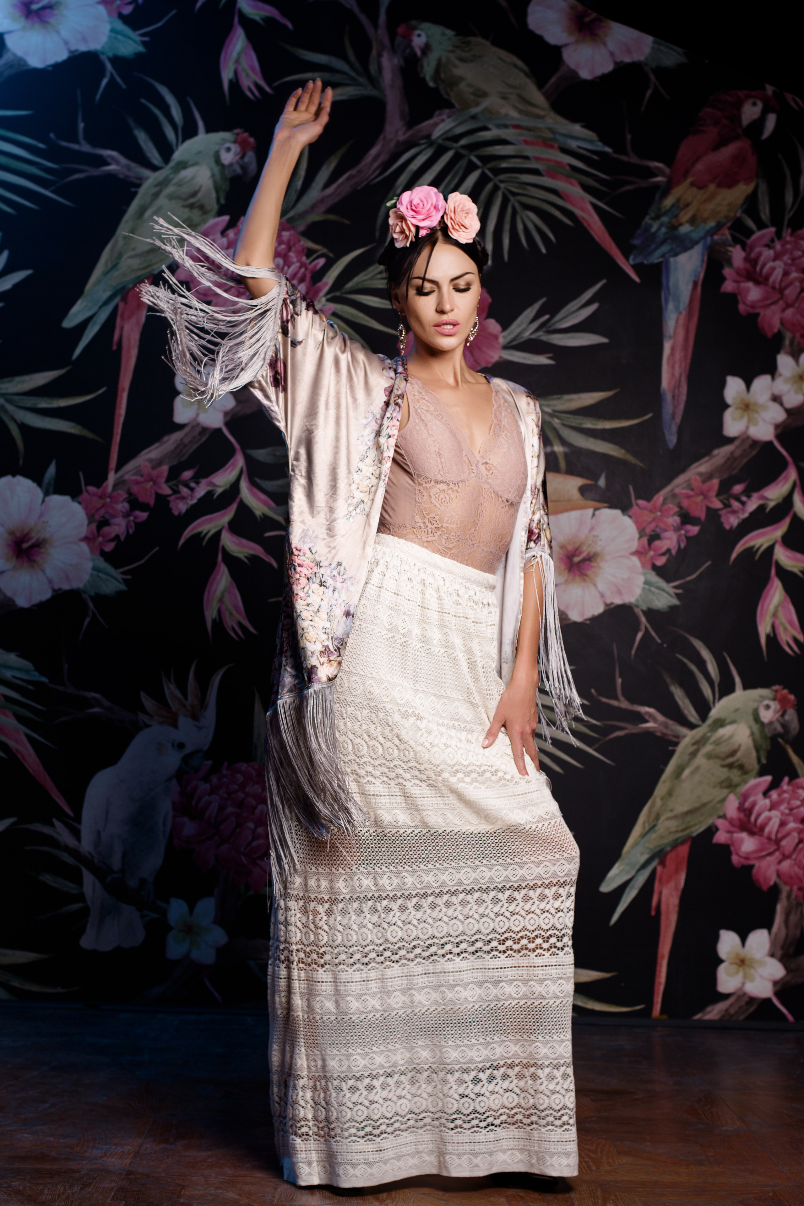 Девушка одетая в стиле Фриды Кало танцует на фоне цветочной стины