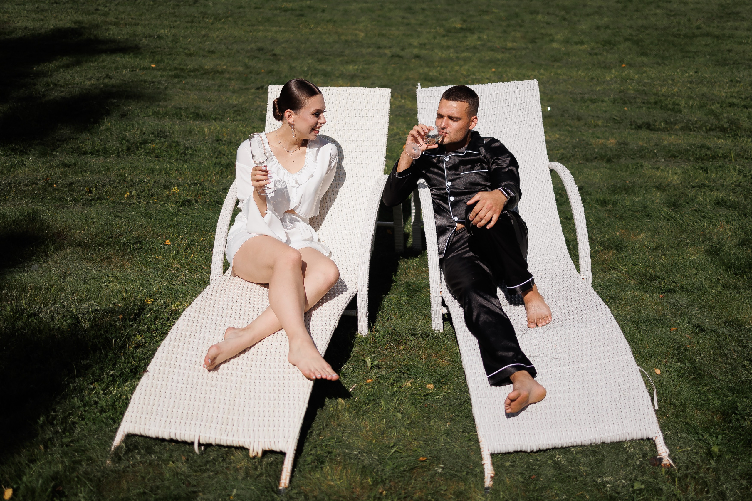 Жених и невеста лежат на шезлонге и пьют шампанское