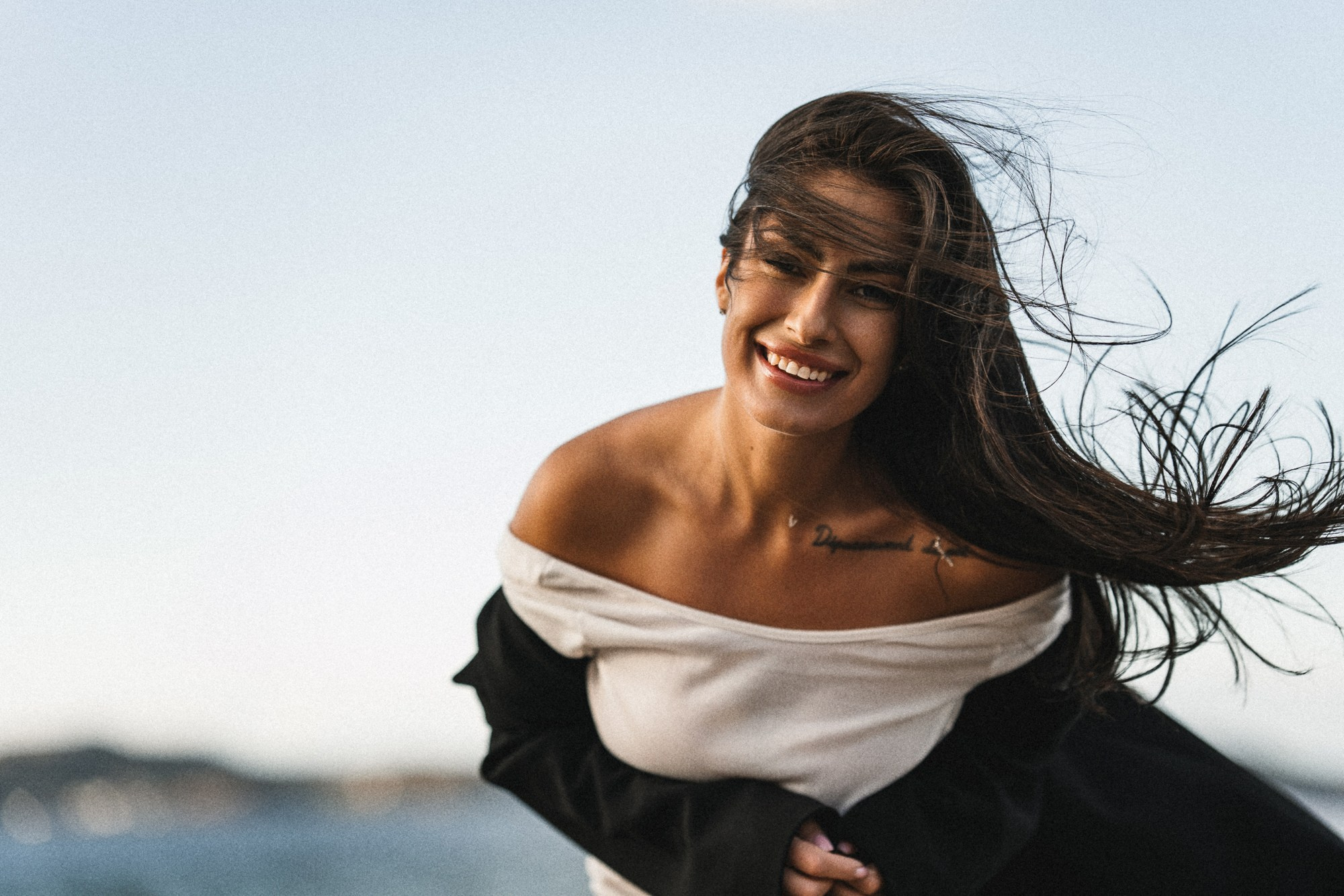 Женский портрет на берегу Баренцева моря, в Териберке. Ветер развевает волосы, светит закатное солнце, изящная девушка смеётся.