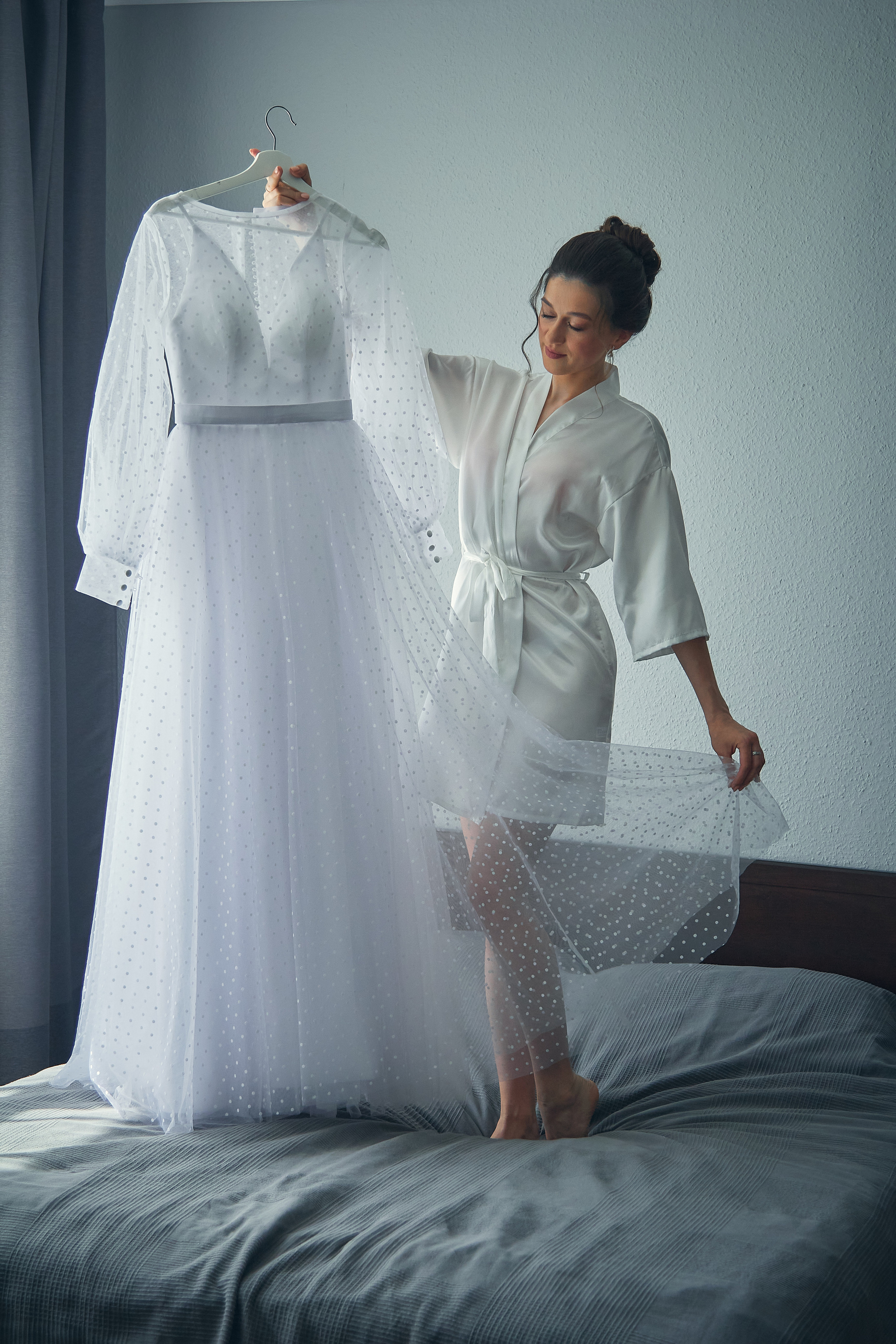 Невеста с платьем в руках на кровати