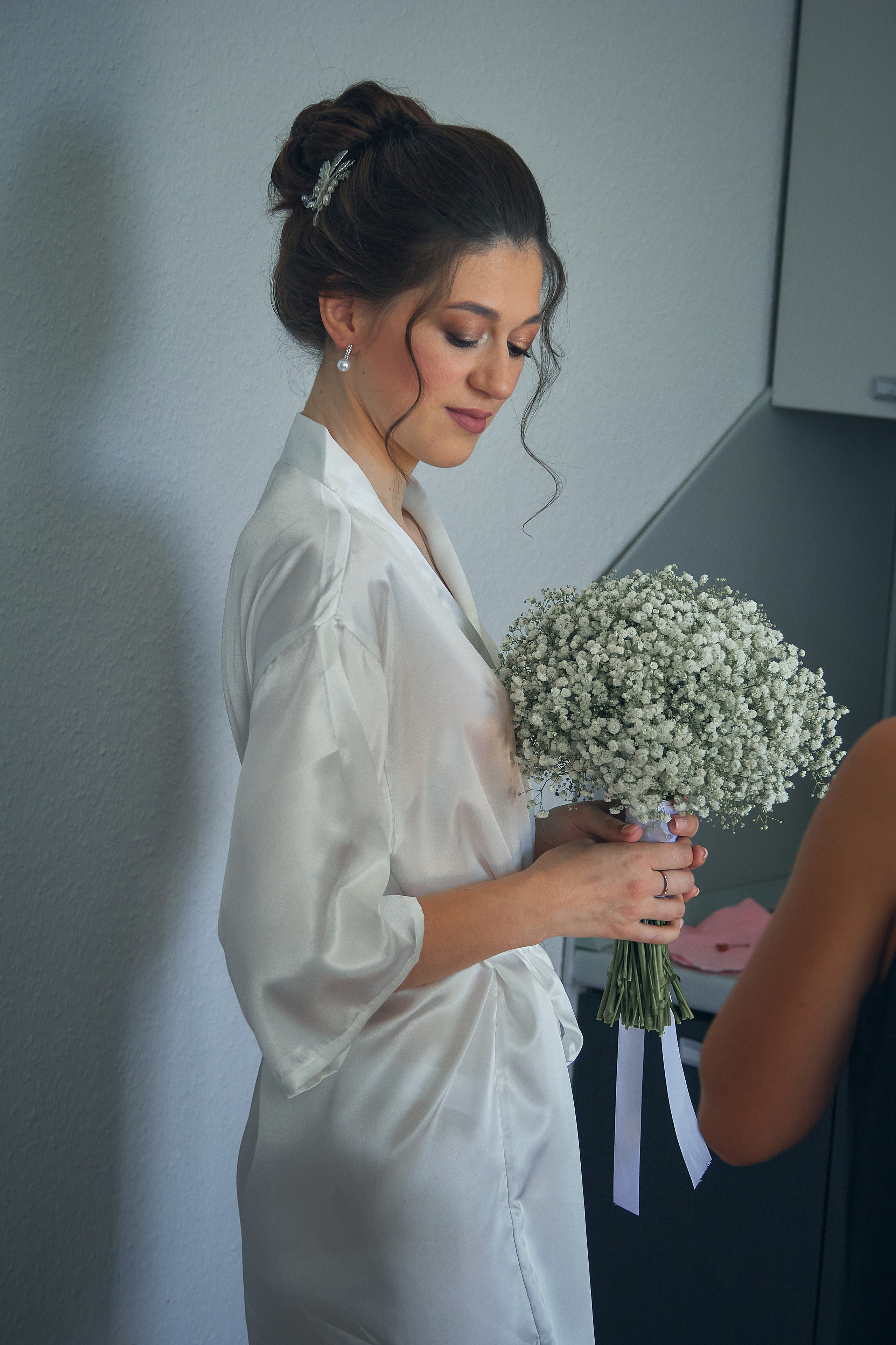 Невеста с букетом стоит возле стены