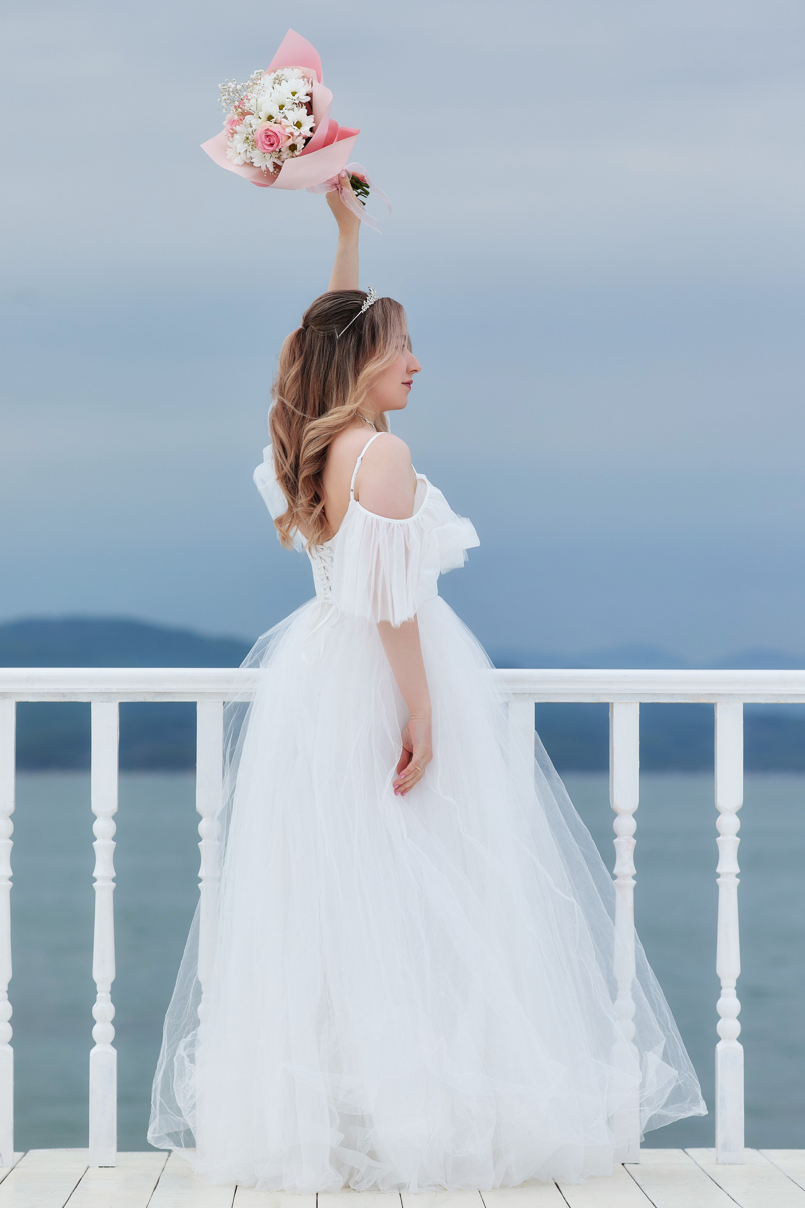 Бросок букета на фоне моря и пирса - идея для свадебной фотосъёмки