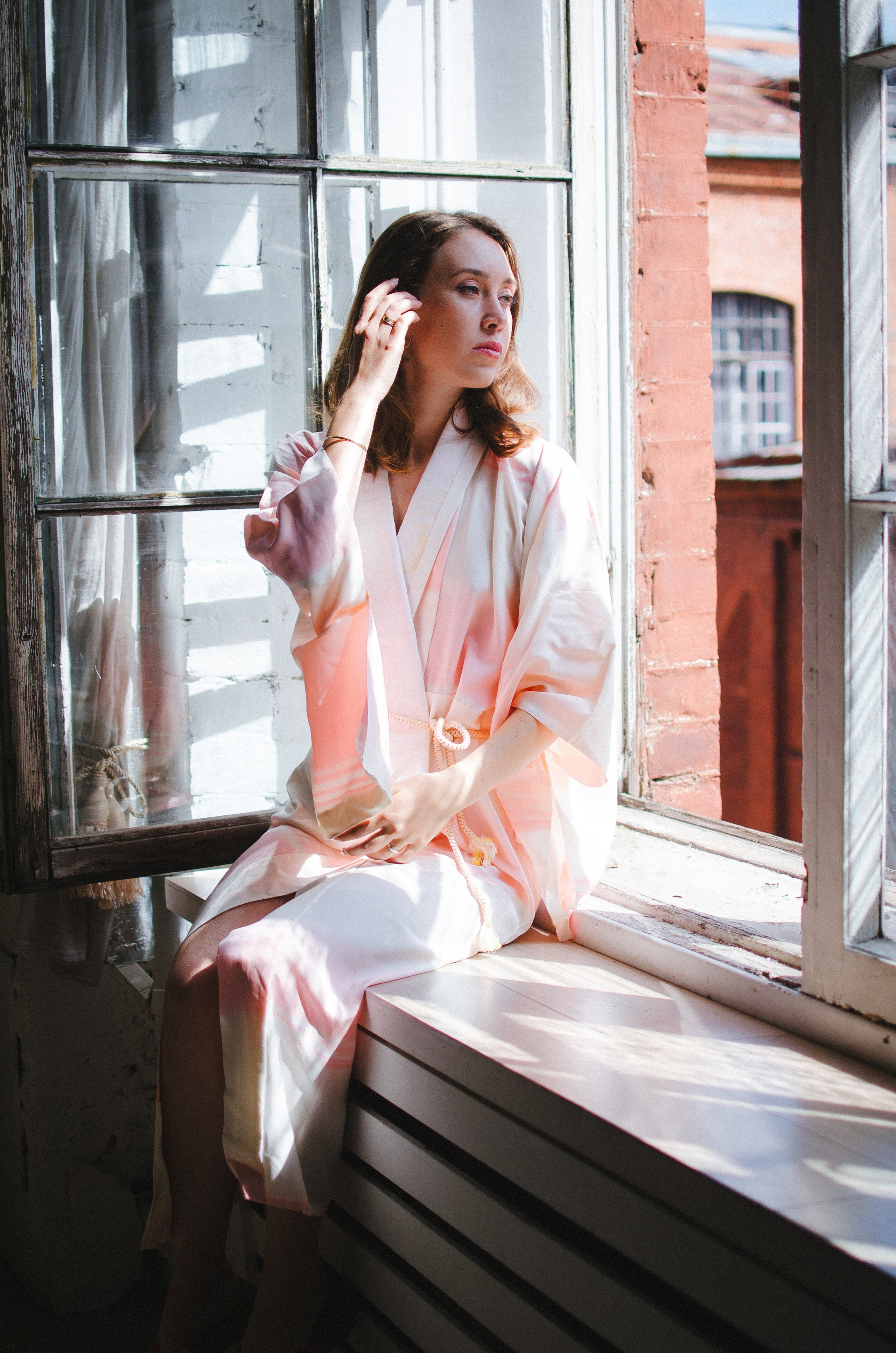 Девушка позирует в светлой студии с хорошим дневным светом от окна.