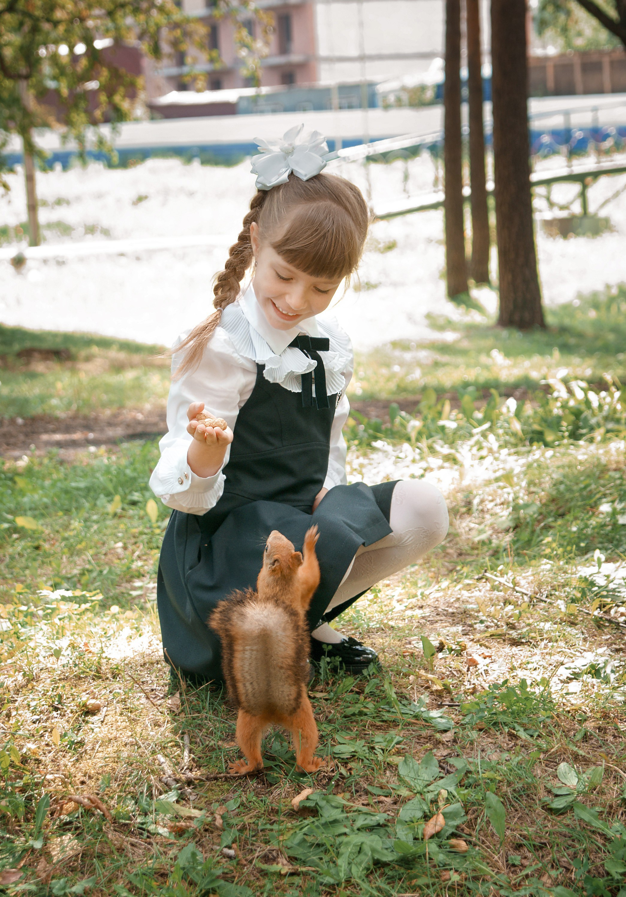 Детская фотосессия осенью - школьница сидя играет с белкой