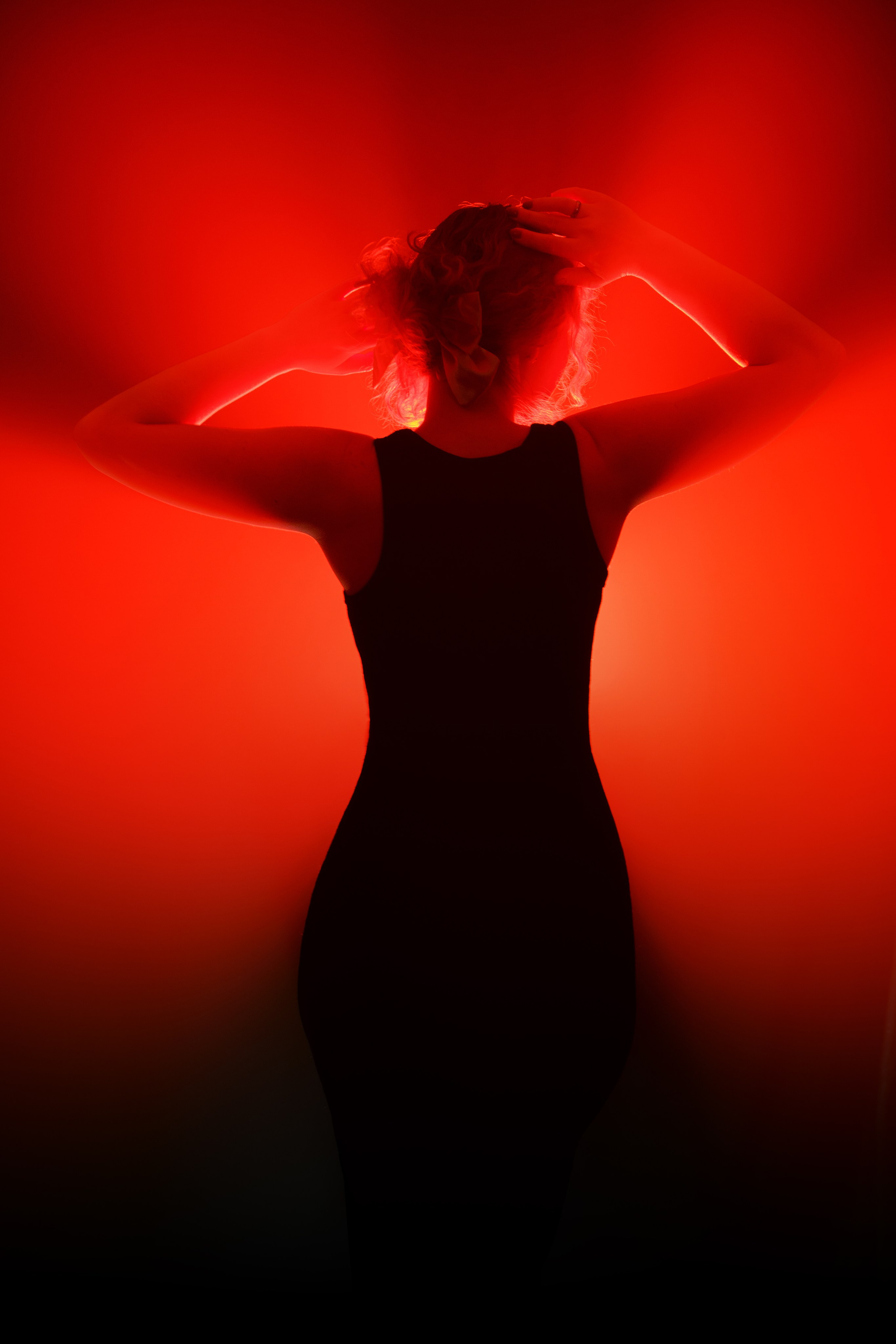 Силуэт девушки в черном платье на фоне красного света. Атмосферная фотография