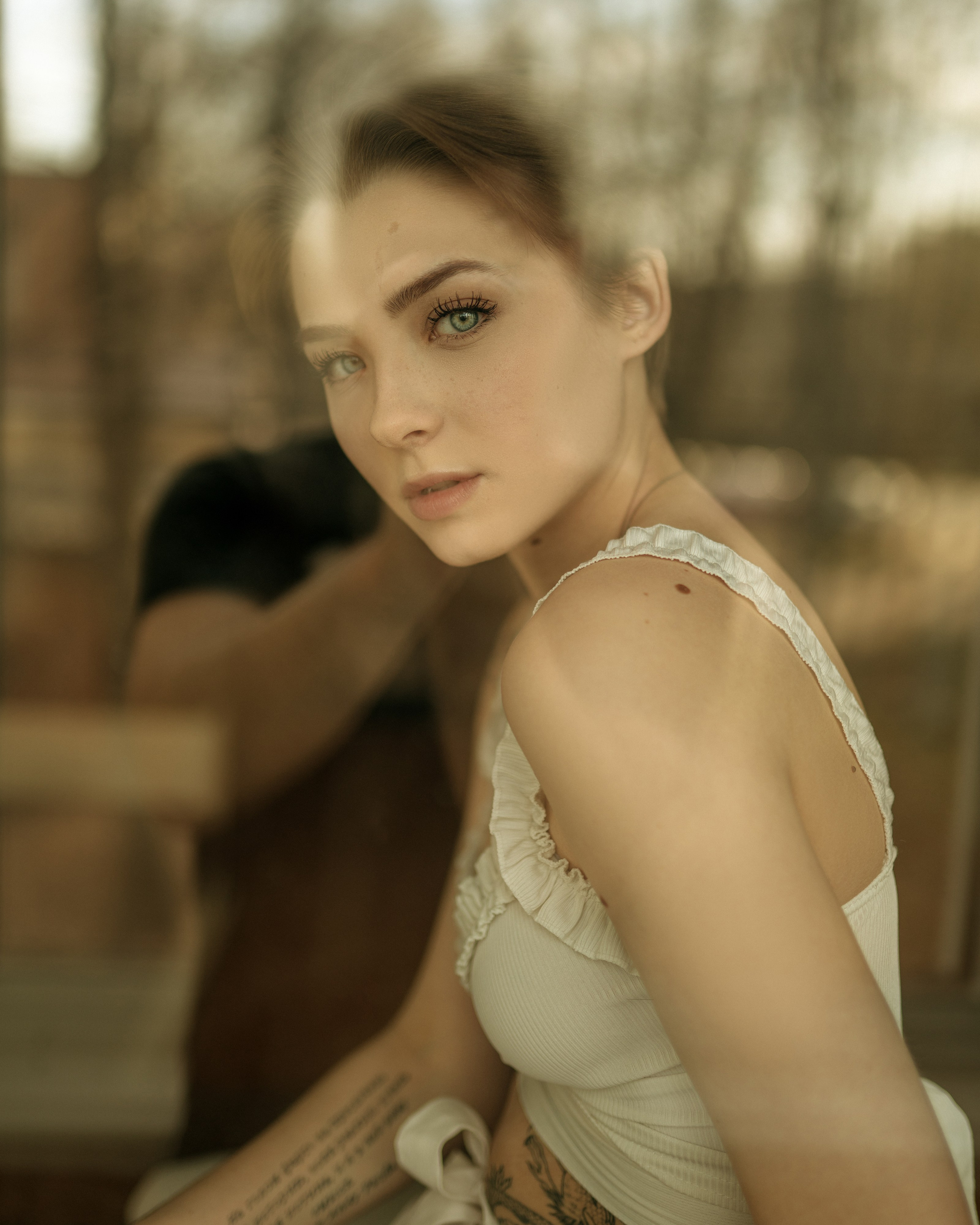 Портрет девушки с короткой причёской  в белом топике за стеклом окна 