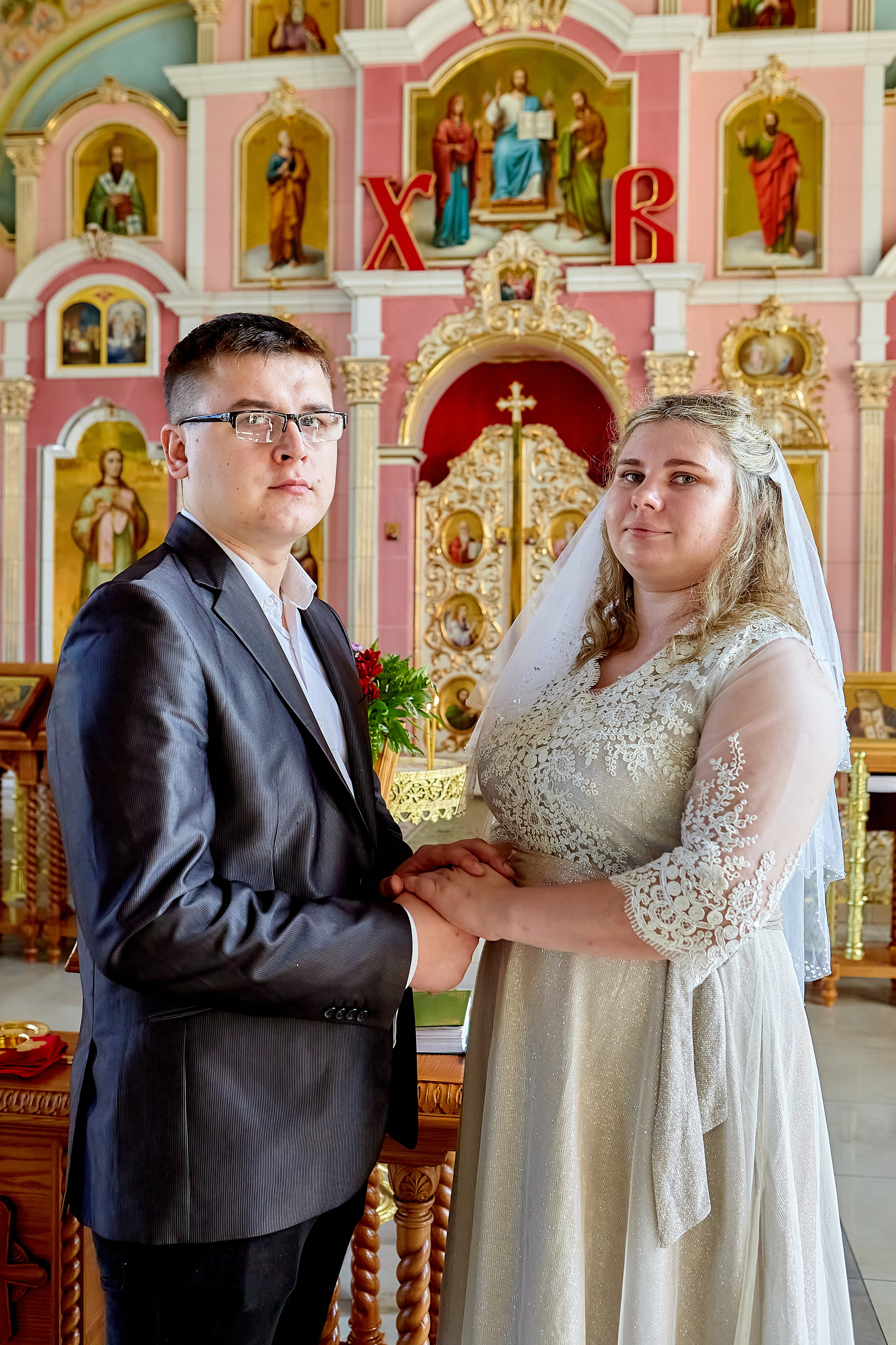 Молодые смотрят на фотографа и держат друг друга за руки