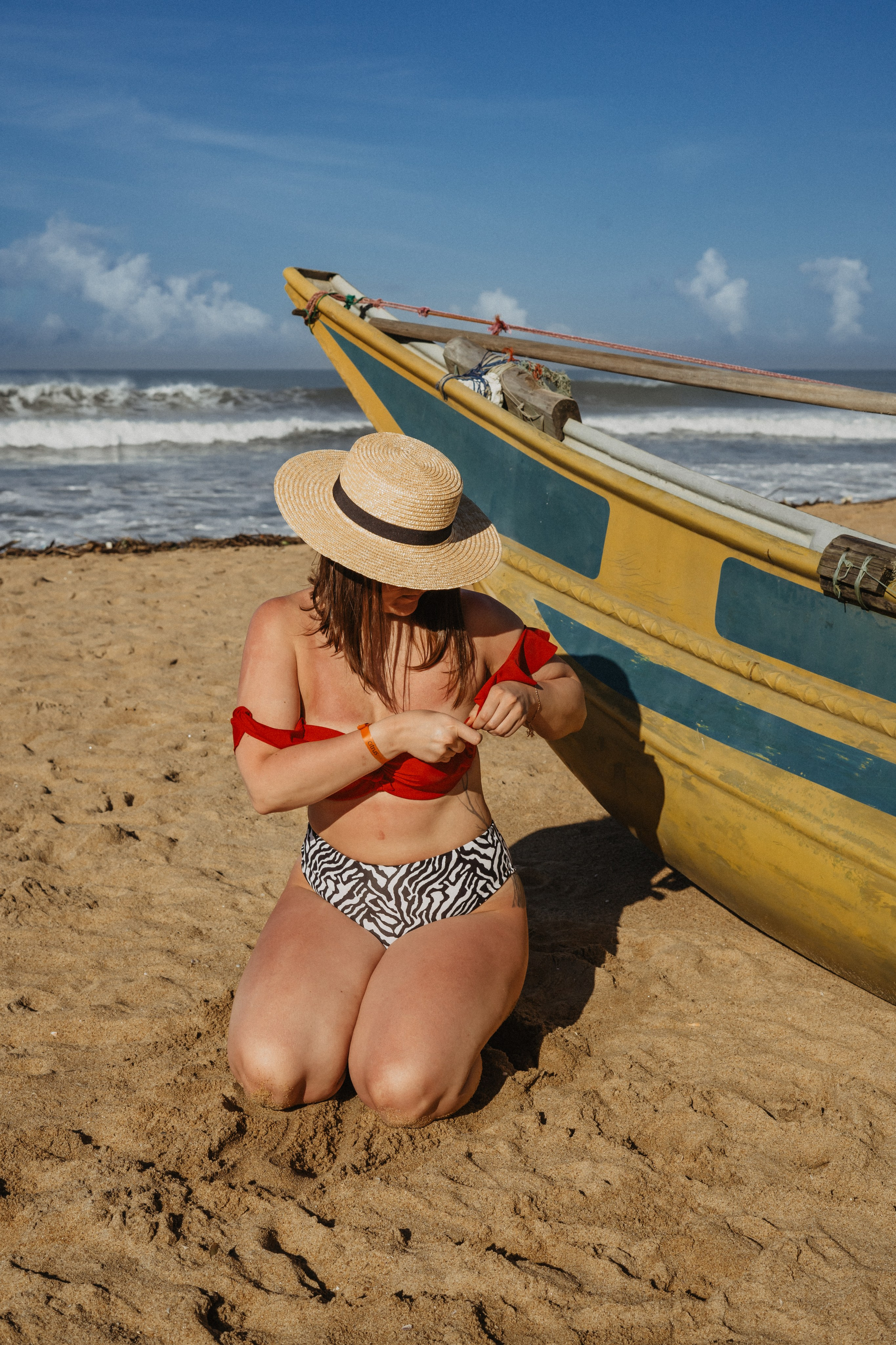 a girl in a straw hat walking along the shore during a photoshoot