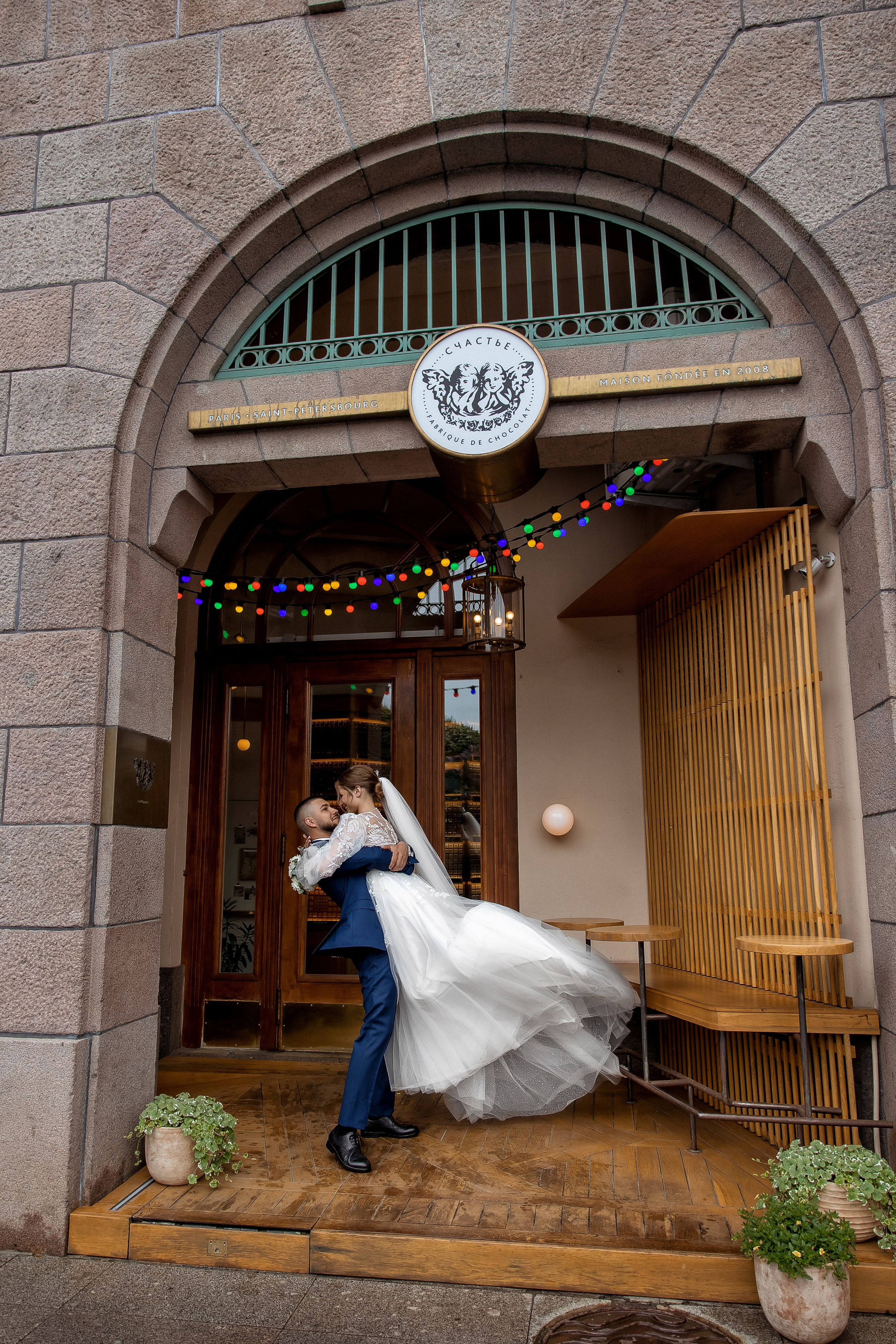 Жених кружит невесту на руках около кондитерской "Счастье"