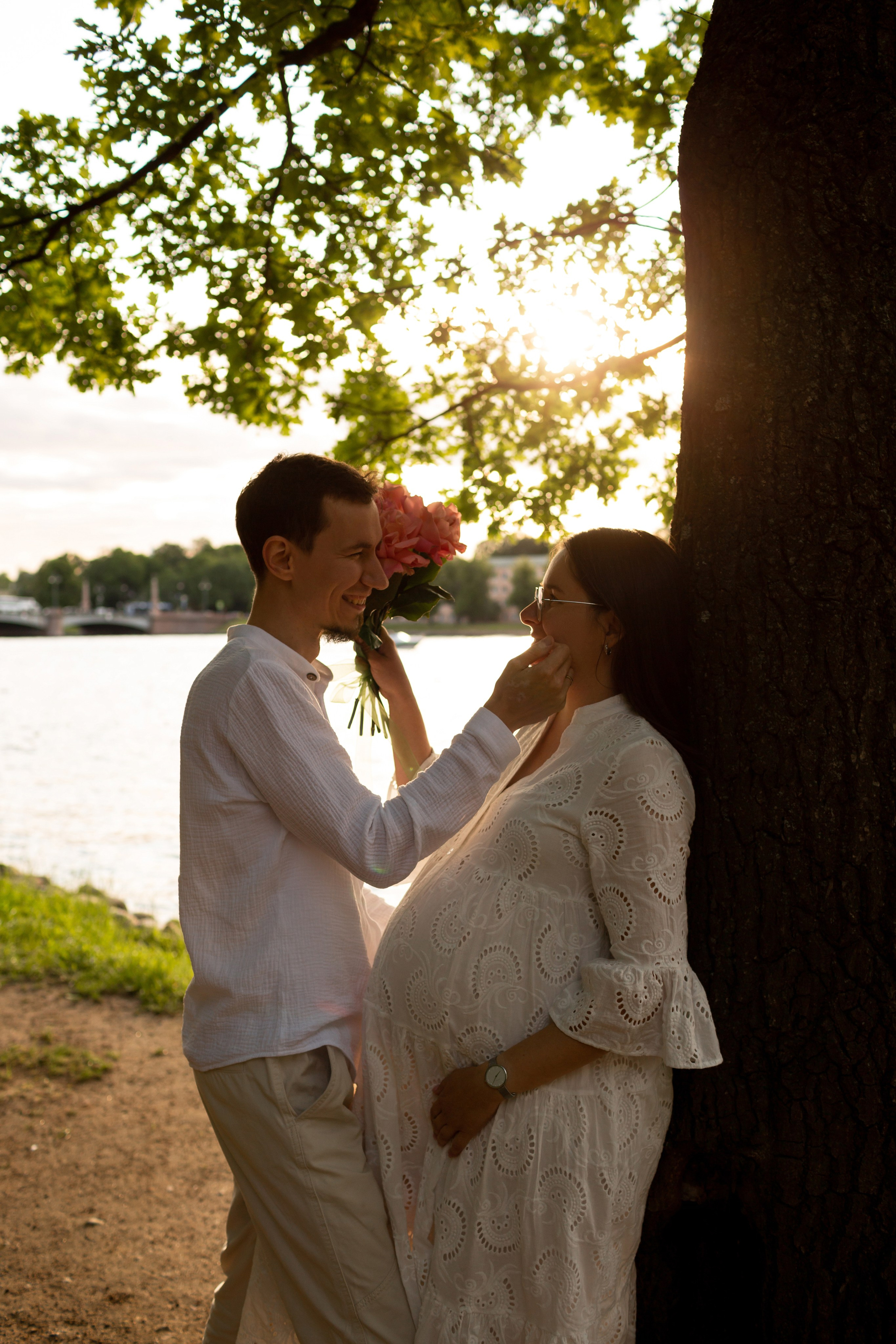 Будущие родители в нежных объятиях на закате.