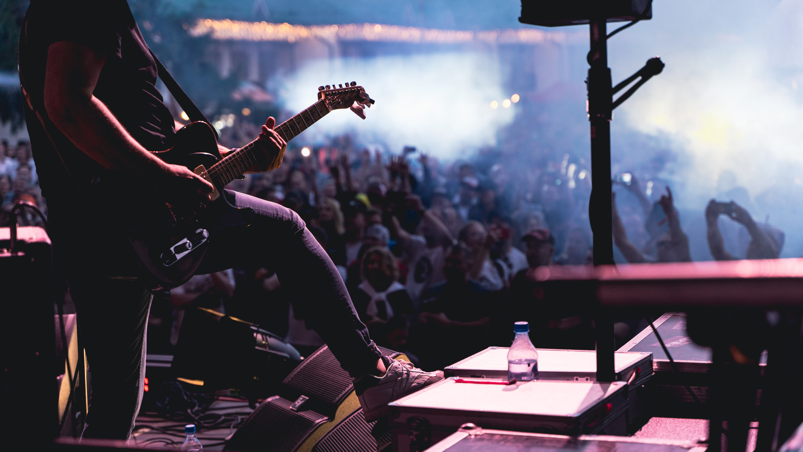 Рок-концерт. Фото гитариста перед толпой фанатов на рок-концерте. Живая музыка гитары на рок-фестивале. Музыканты играют рок и заводят толпу. Рокнролл жив. 