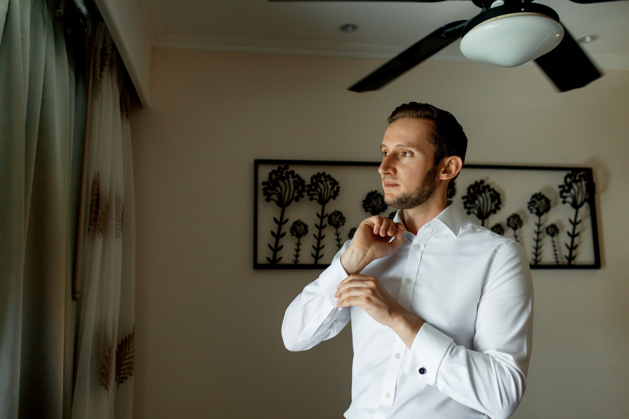 жених одевает запонки, стоя у окна