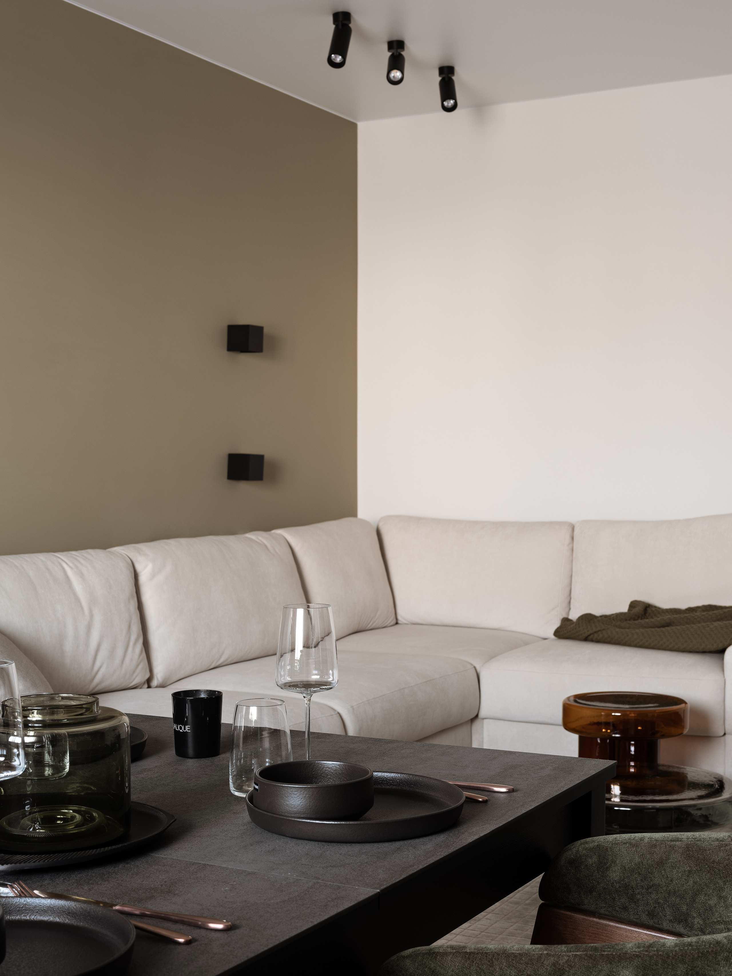 Интерьер гостиной с большим бежевым диваном, современным черным столом и сервировкой; дизайн квартиры от Екатерины Мищенко, интерьерная фотосъемка Сергея Денисенко.